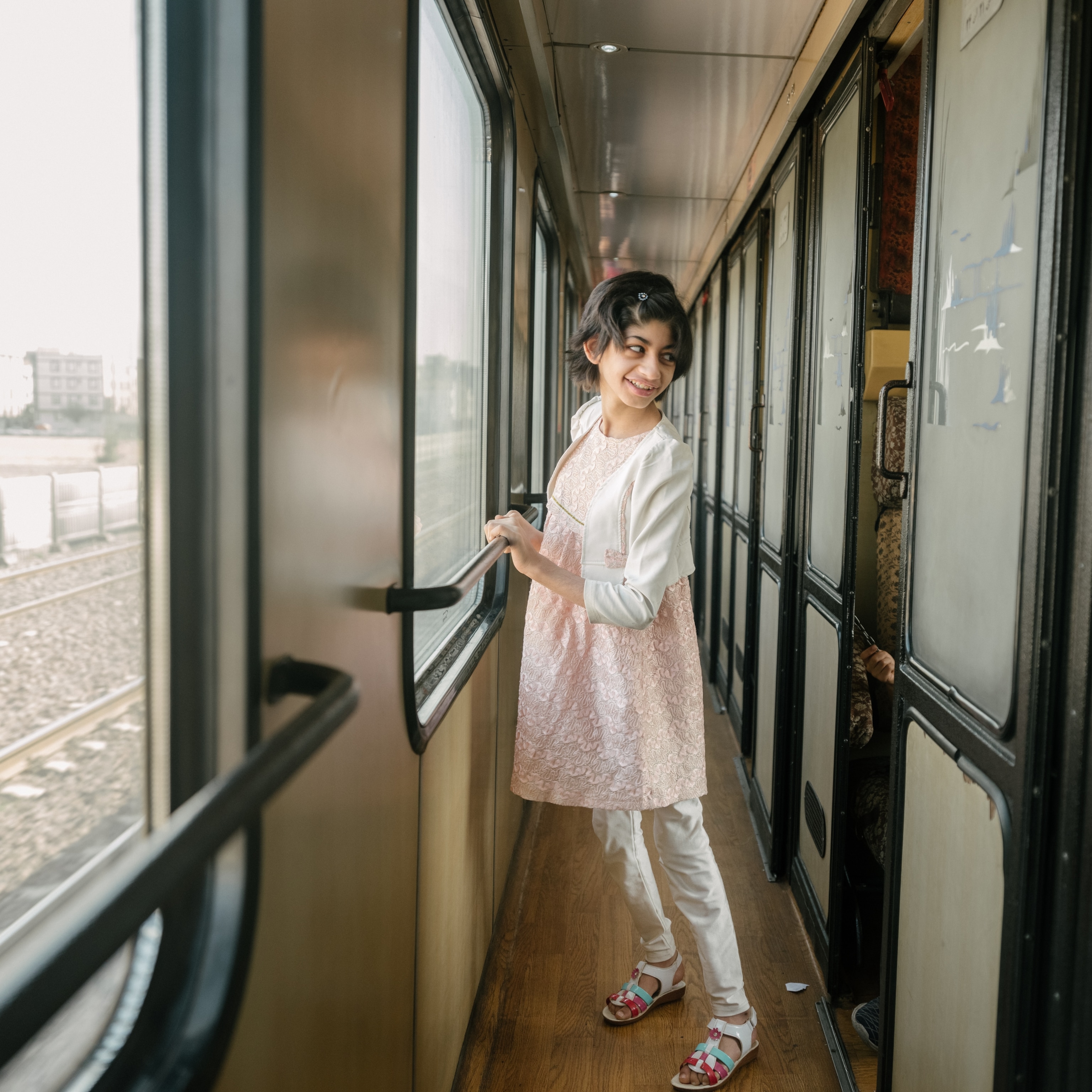 A little girl looks out the train window as the train travels