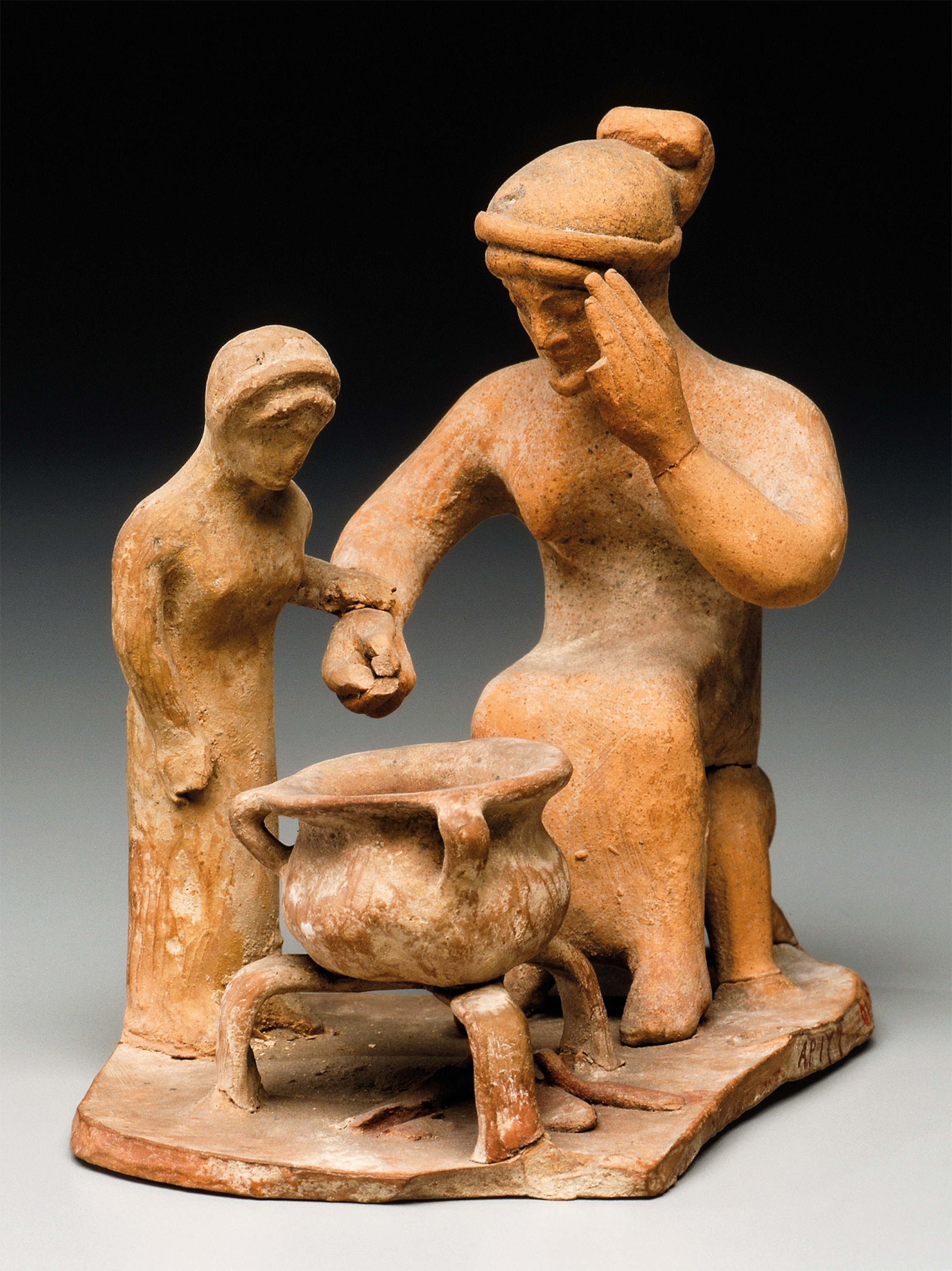 A woman cooks as a young girl looks on in a fifth-century B.C. terra-cotta figure from Tanagra, Greece.