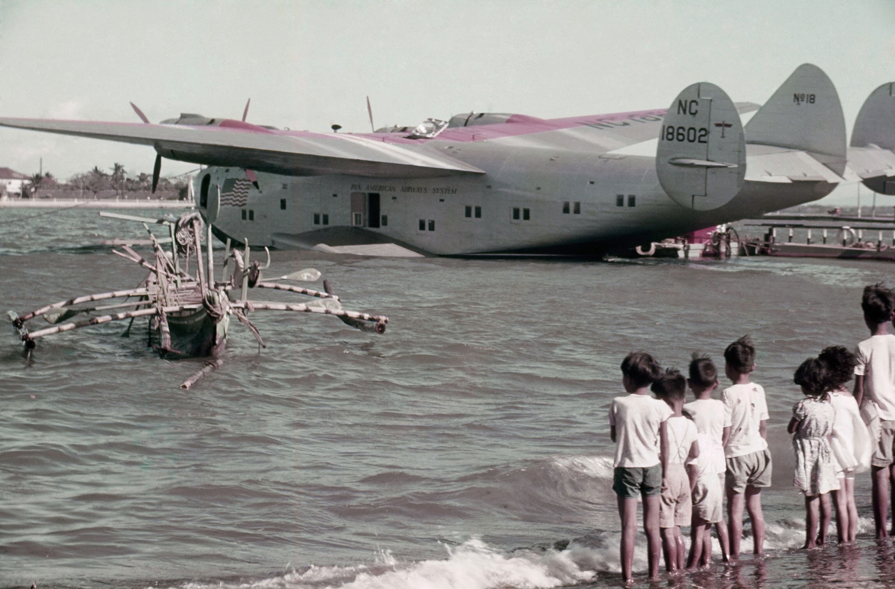 children watching a floating plane as sits next to a dock in the Philippines