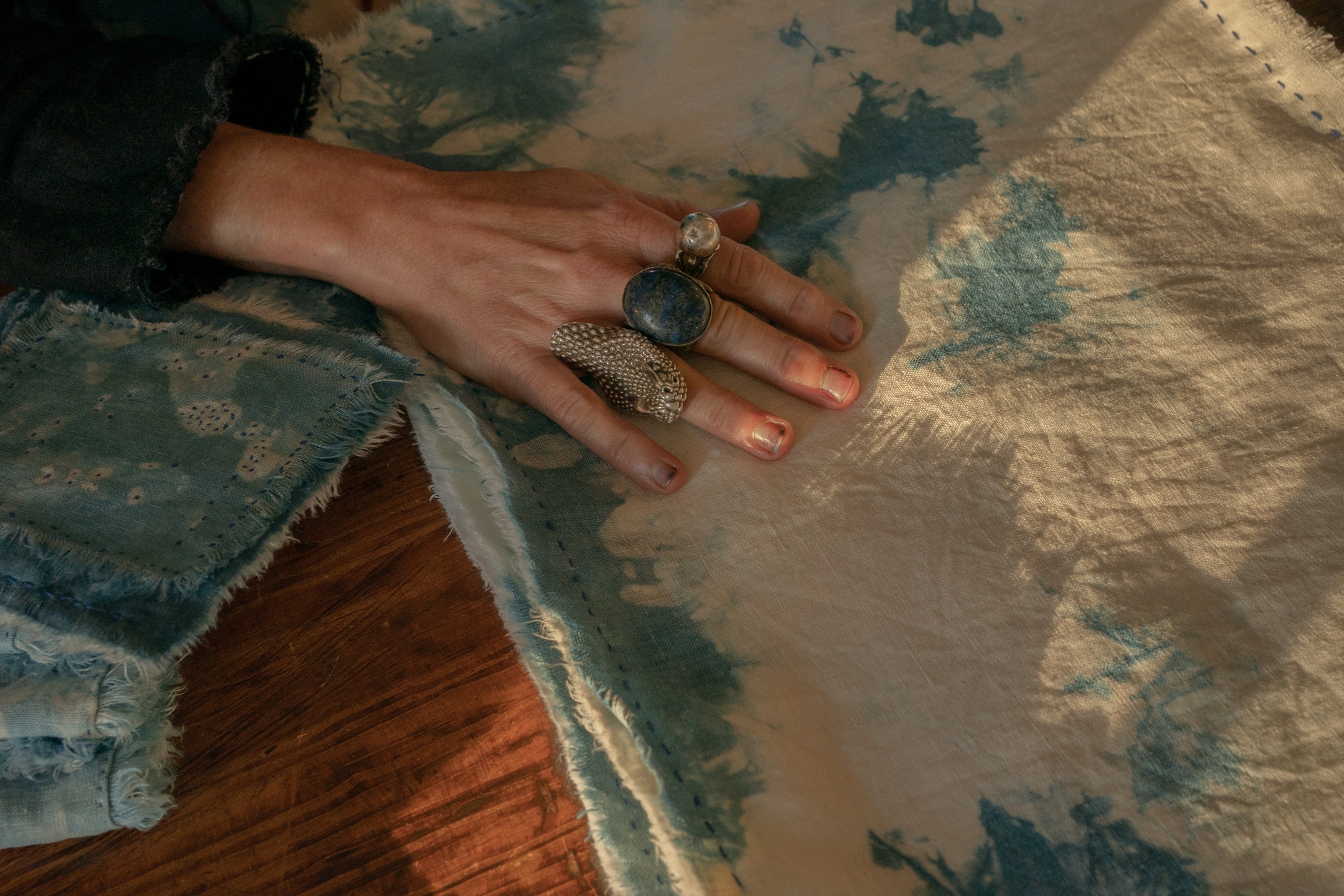 Leah Magar rests her hand on a hand stitched, hand dyed linen scarf with indigo dyed linen thread, at her textile design studio in Charleston, South Carolina