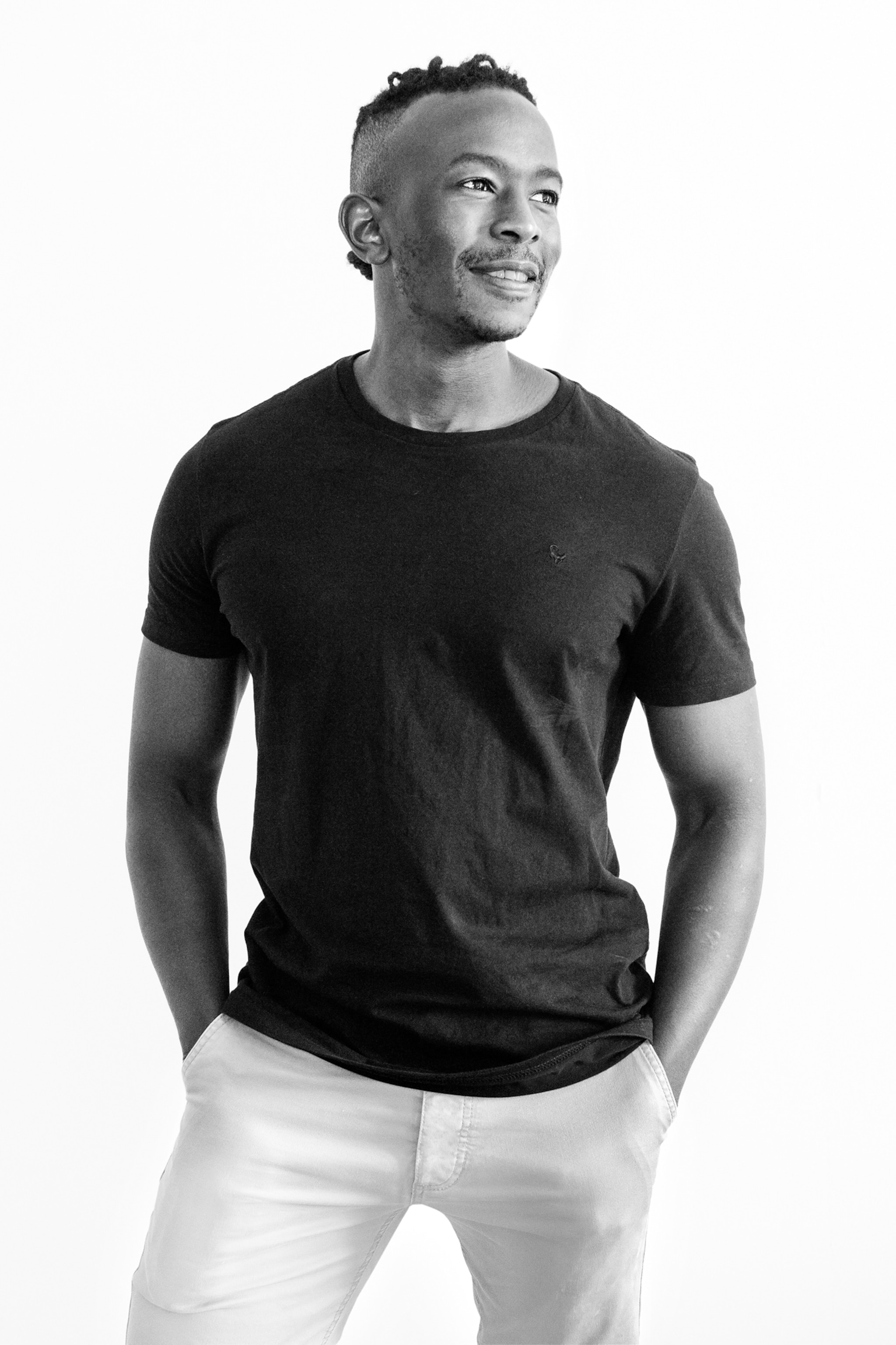 Young athletic African man with his hands in the pockets of his white pants.