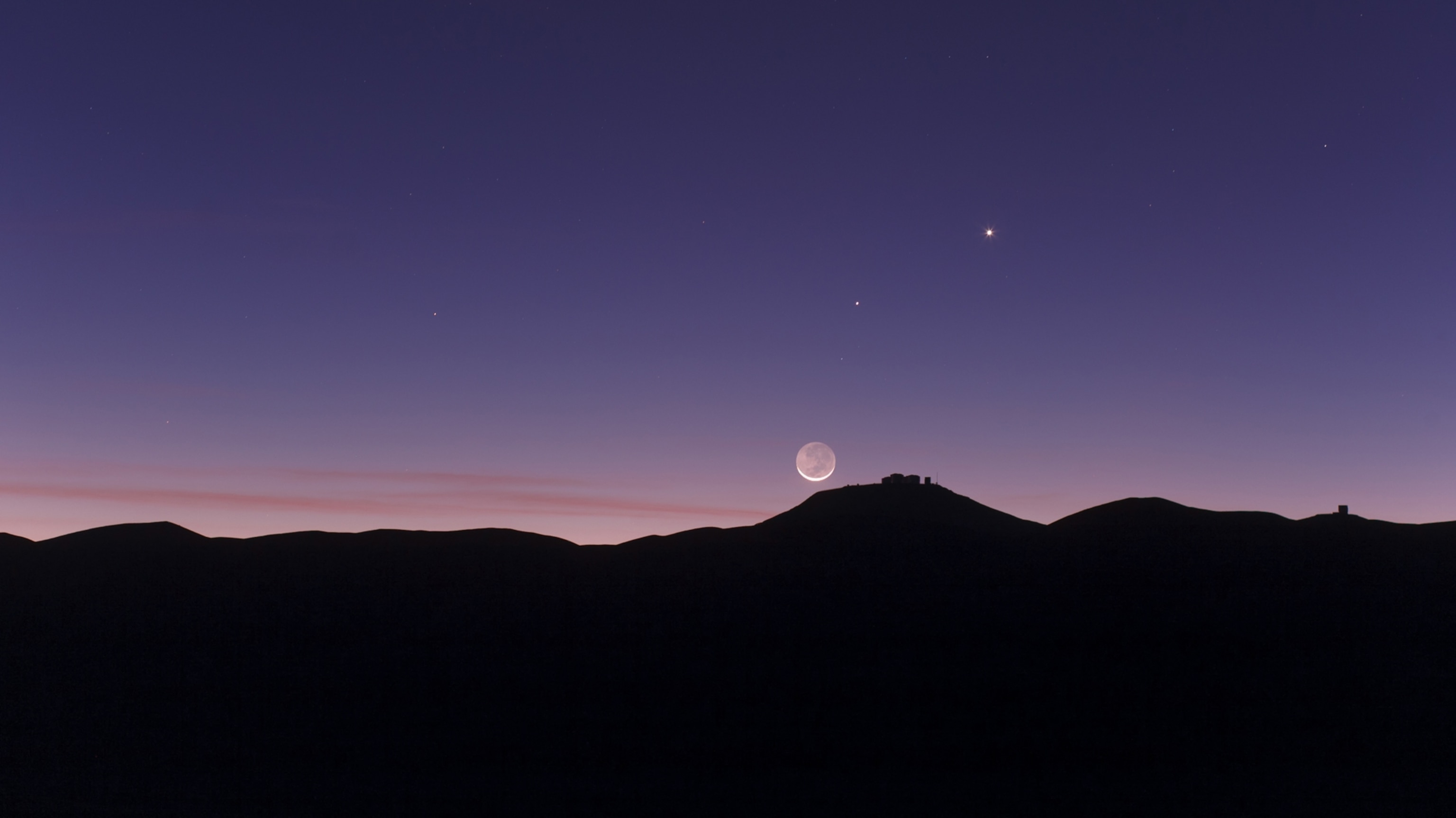 A mountainous skyline with a visible alignment of the new moon with Venus and Mercury.