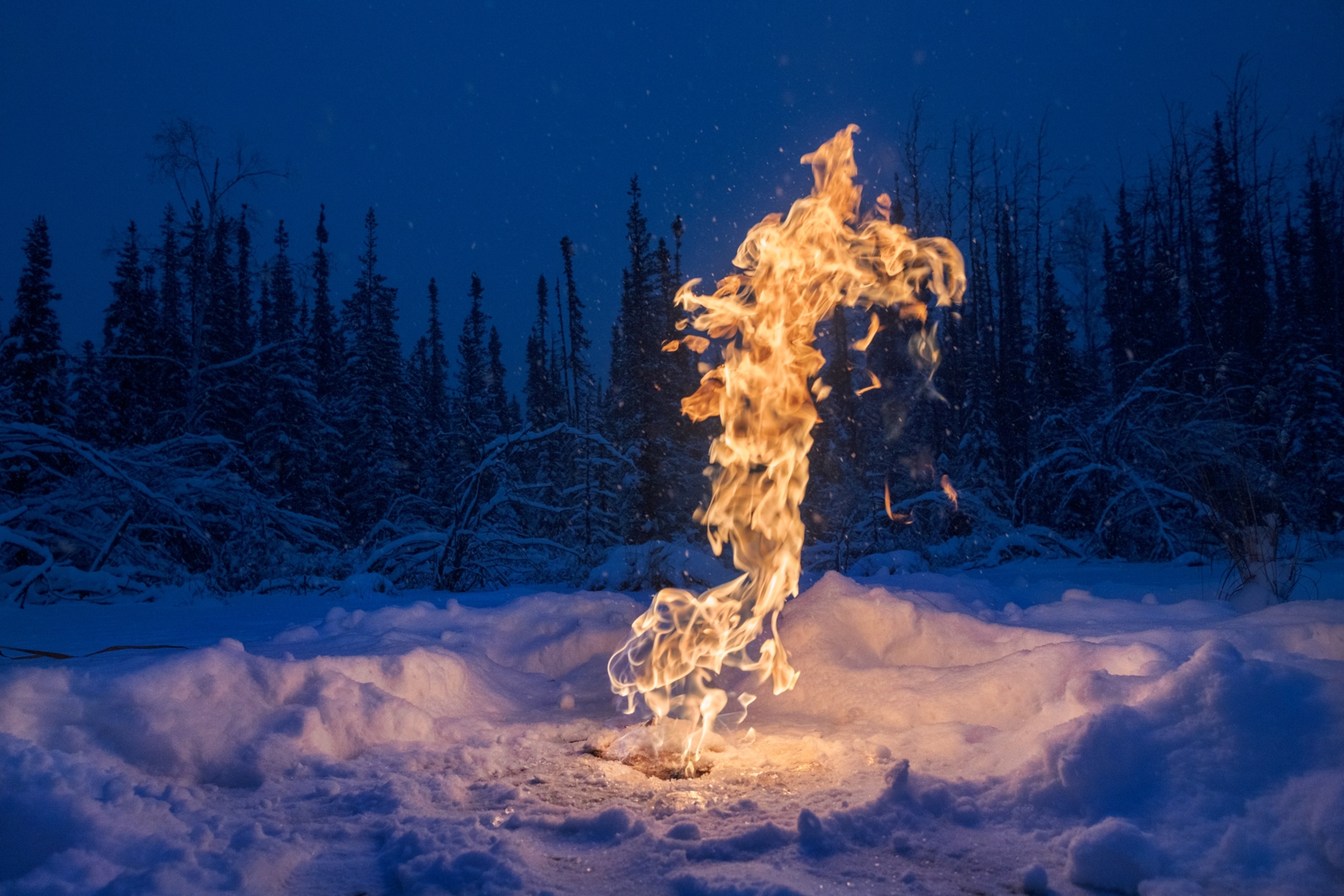 flame from hole in ice and snow at night.