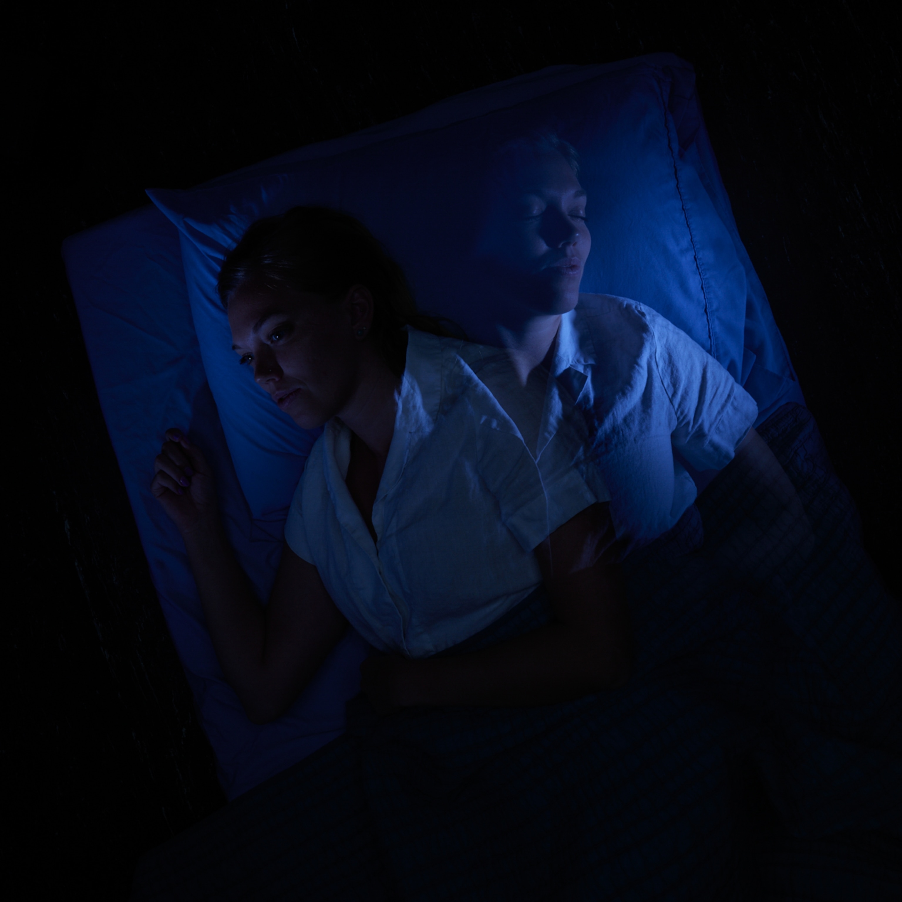 A long-exposure image shows a woman in bed as she attempts to fall asleep.