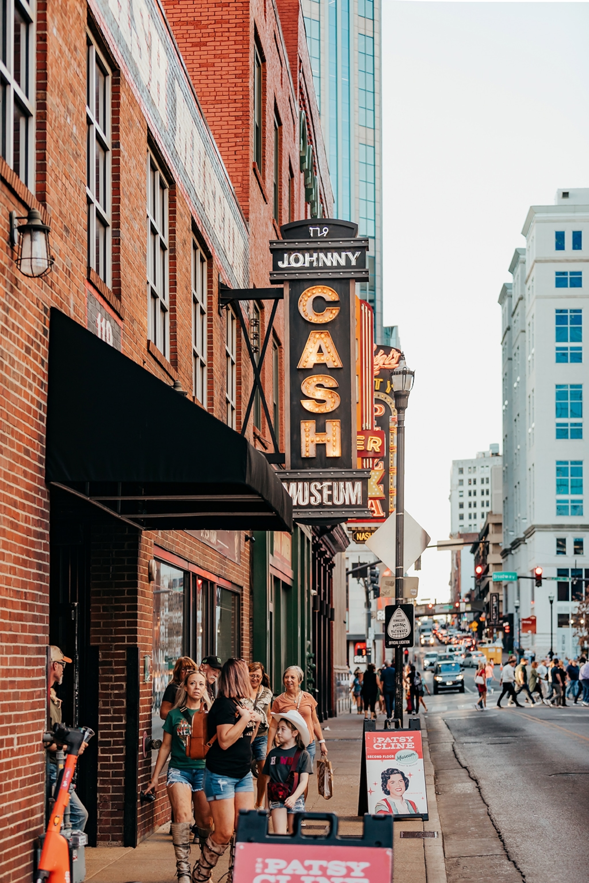 A downtown scene focusing on a brick building with 'Johnny Cash' signs hanging from the side of the facade.