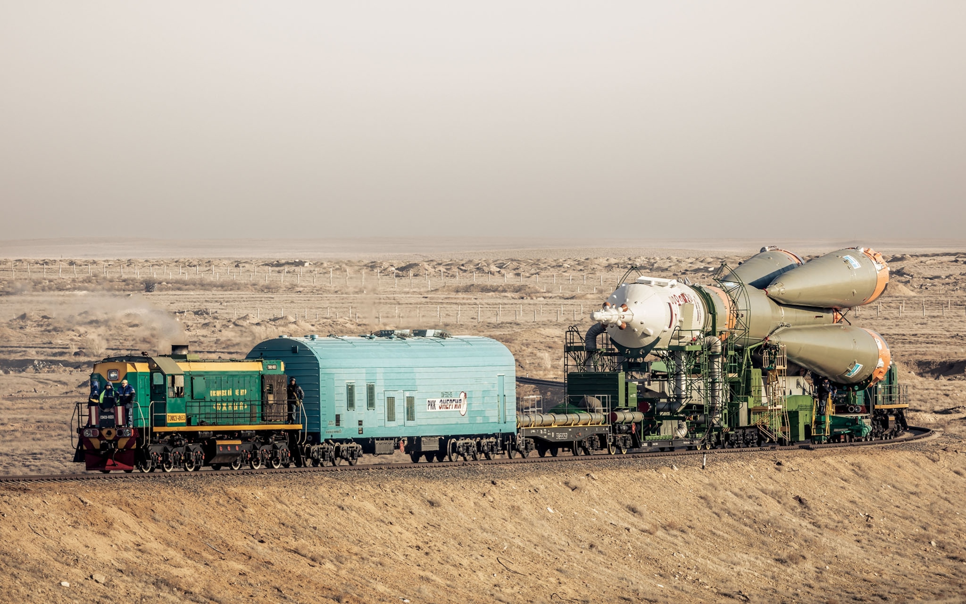 a space shop being transported on a train in a barren landscape