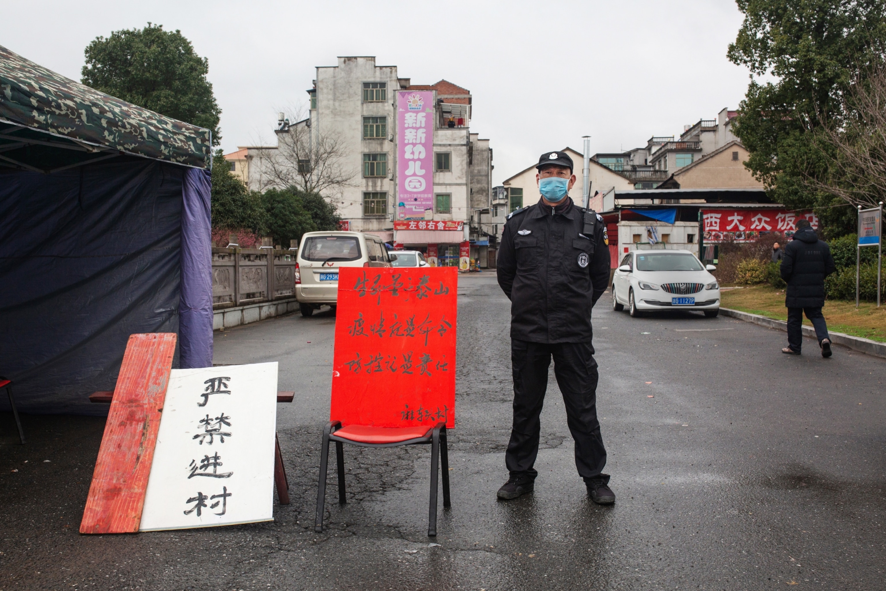 masked policeman standing by red banner.