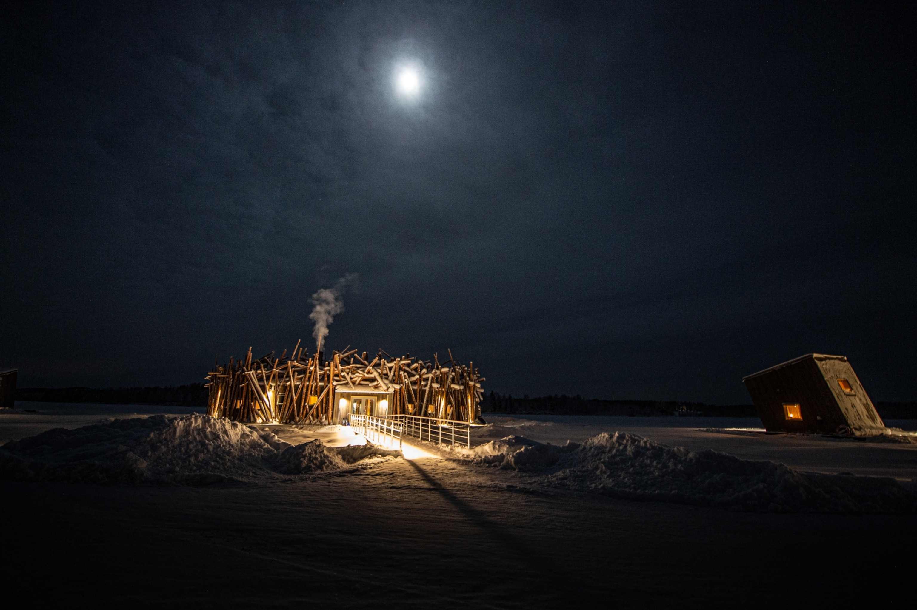 The snow-covered main building and a hotel unit seen lit under a full moon.