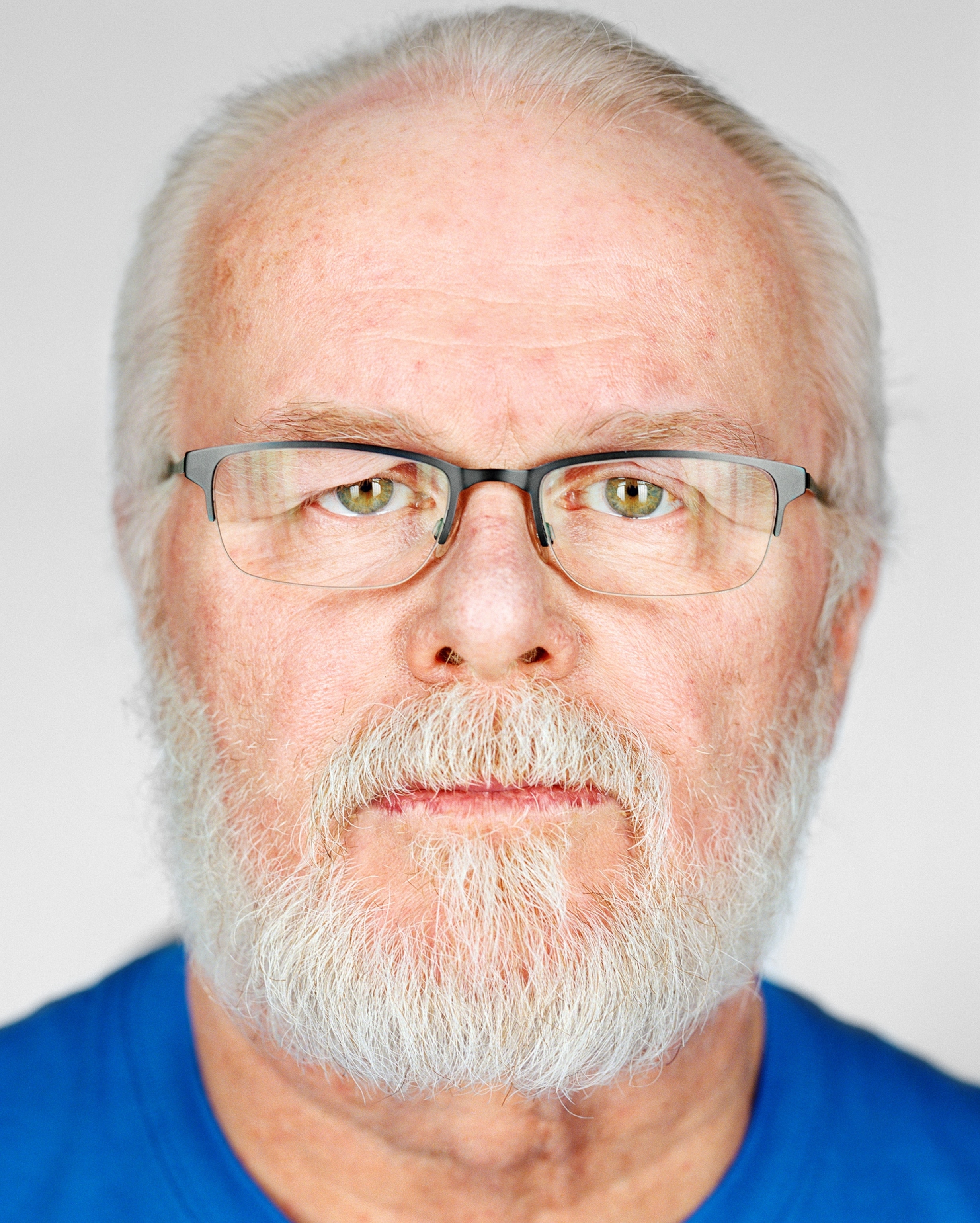man with gray hair and beard in eyeglasses.