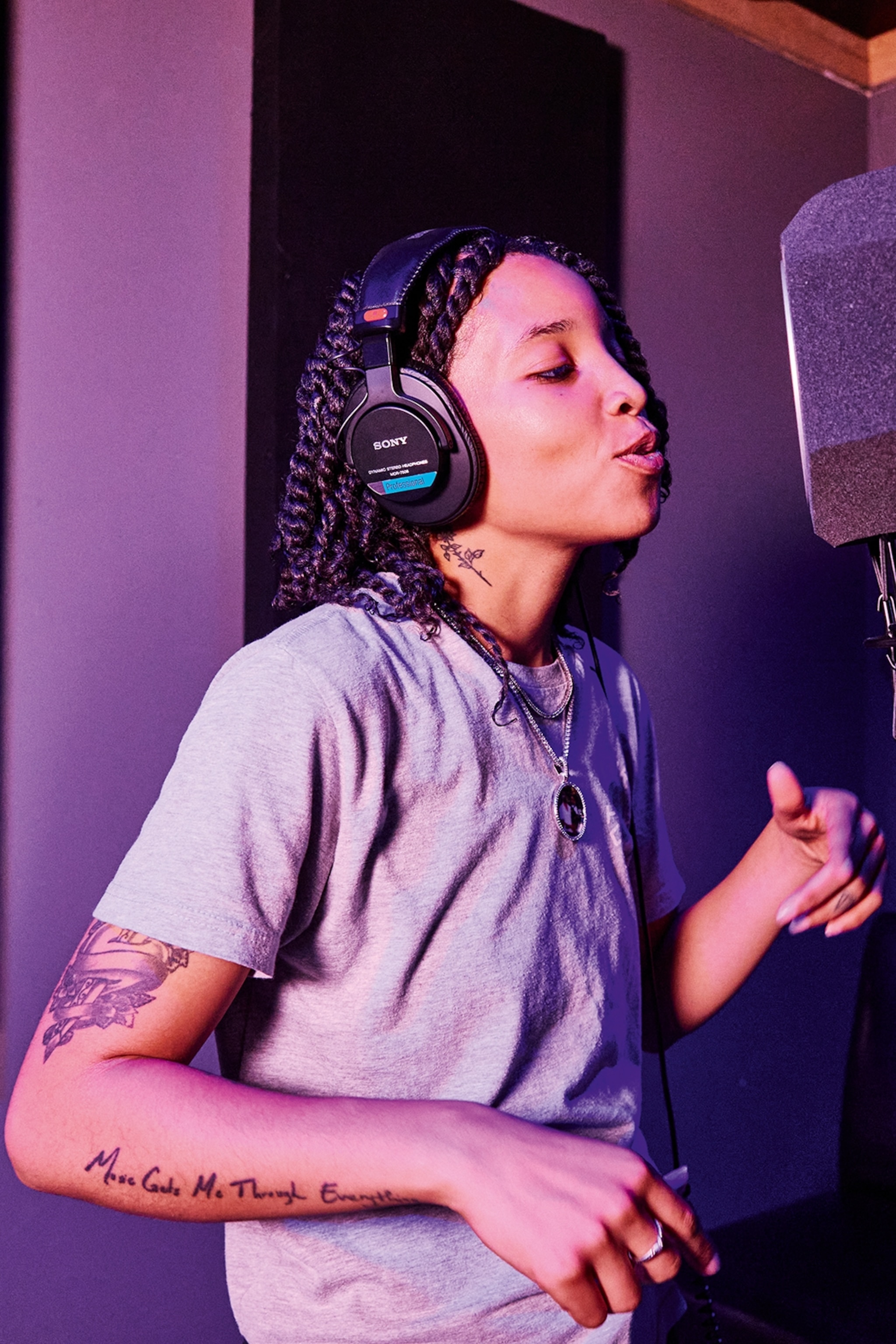 A young, black woman recording vocals in a studio.