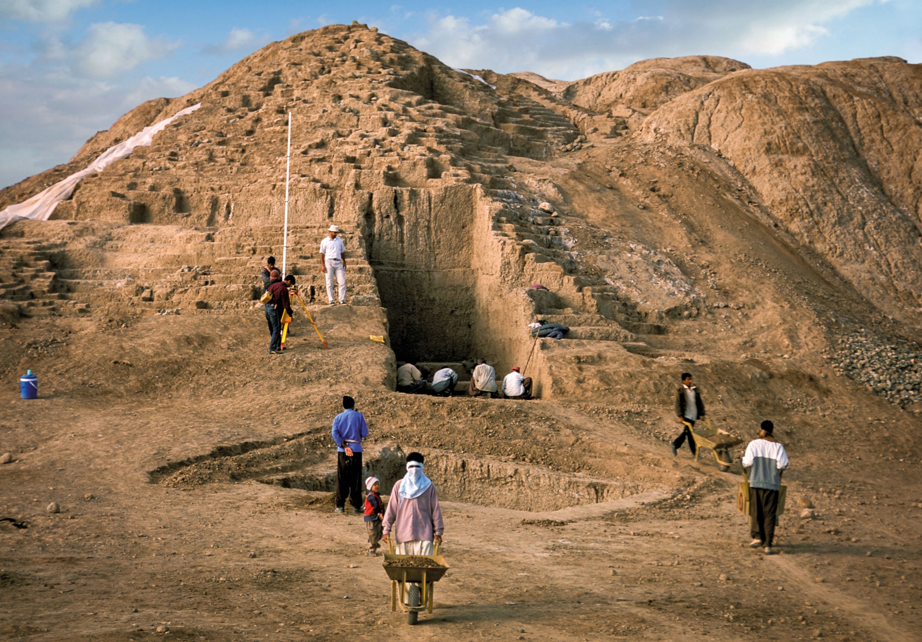 People move wheelbarrows about an excavation site