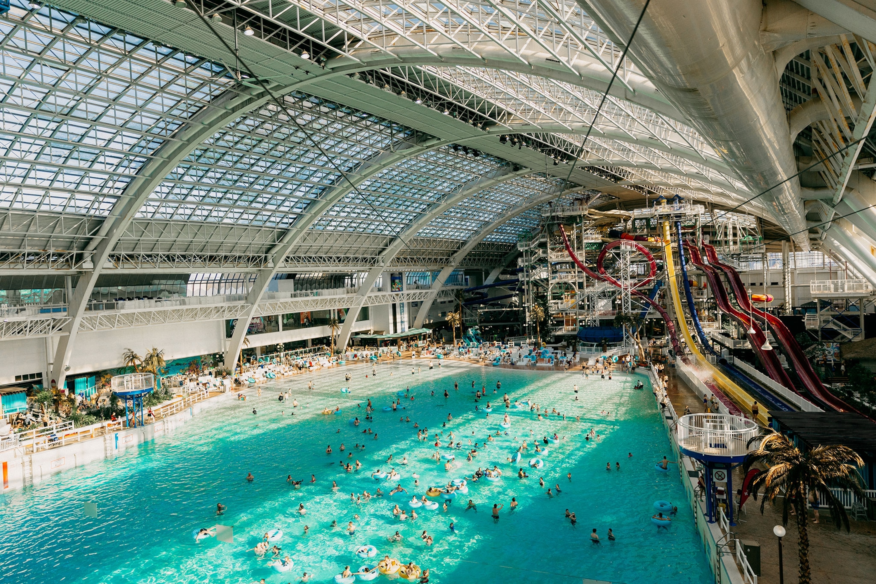 People swim in a huge pool next to several multi-coloured waterslides.