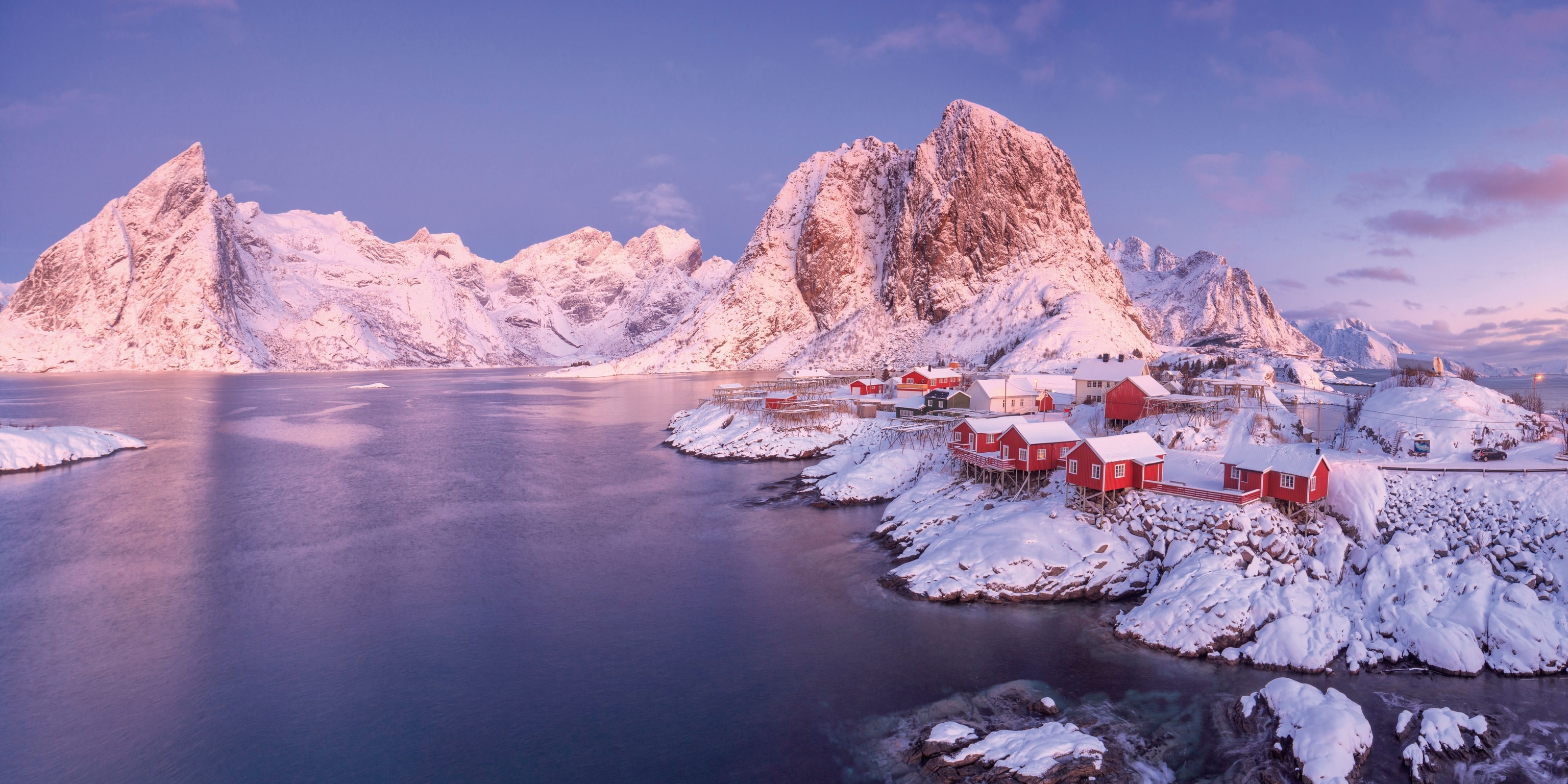 red and white fishing village pictured below snowcapped mountain peaks