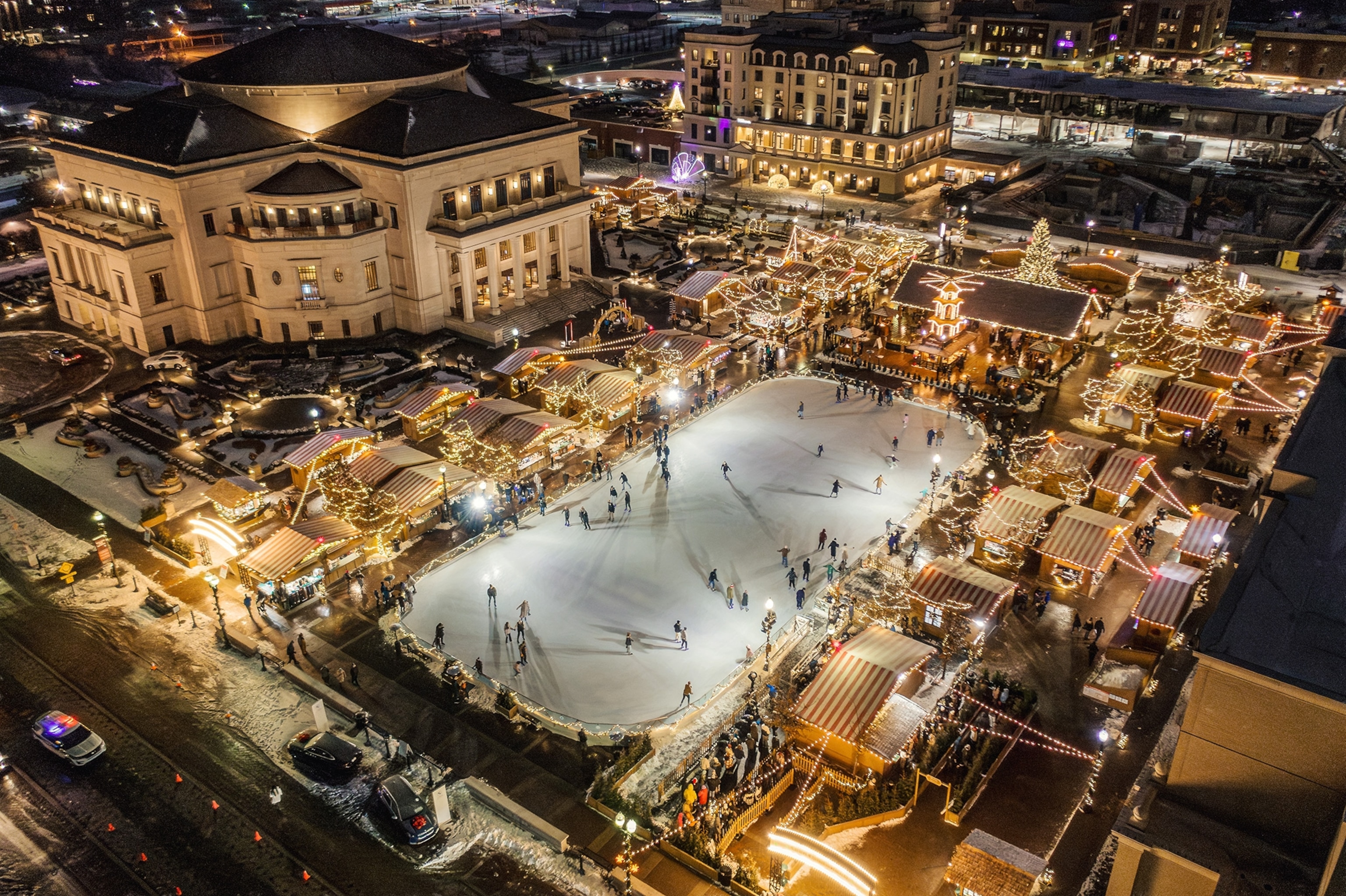 Areal of the Carmel Christkindlmarkt with an ice skating rink and shops at night.
