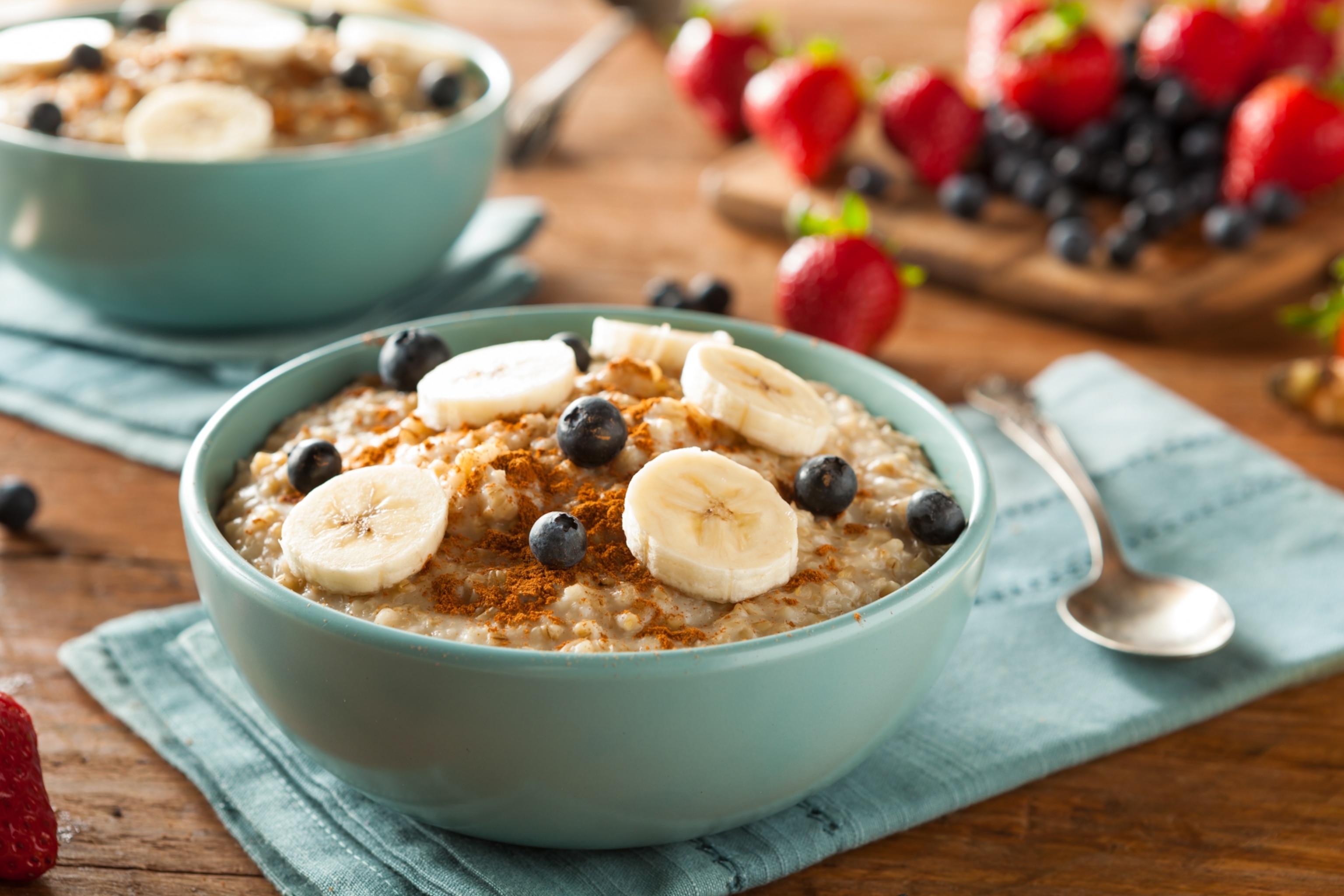 A bowl of oatmeal topped with cinnamon, banana slices, and blueberries