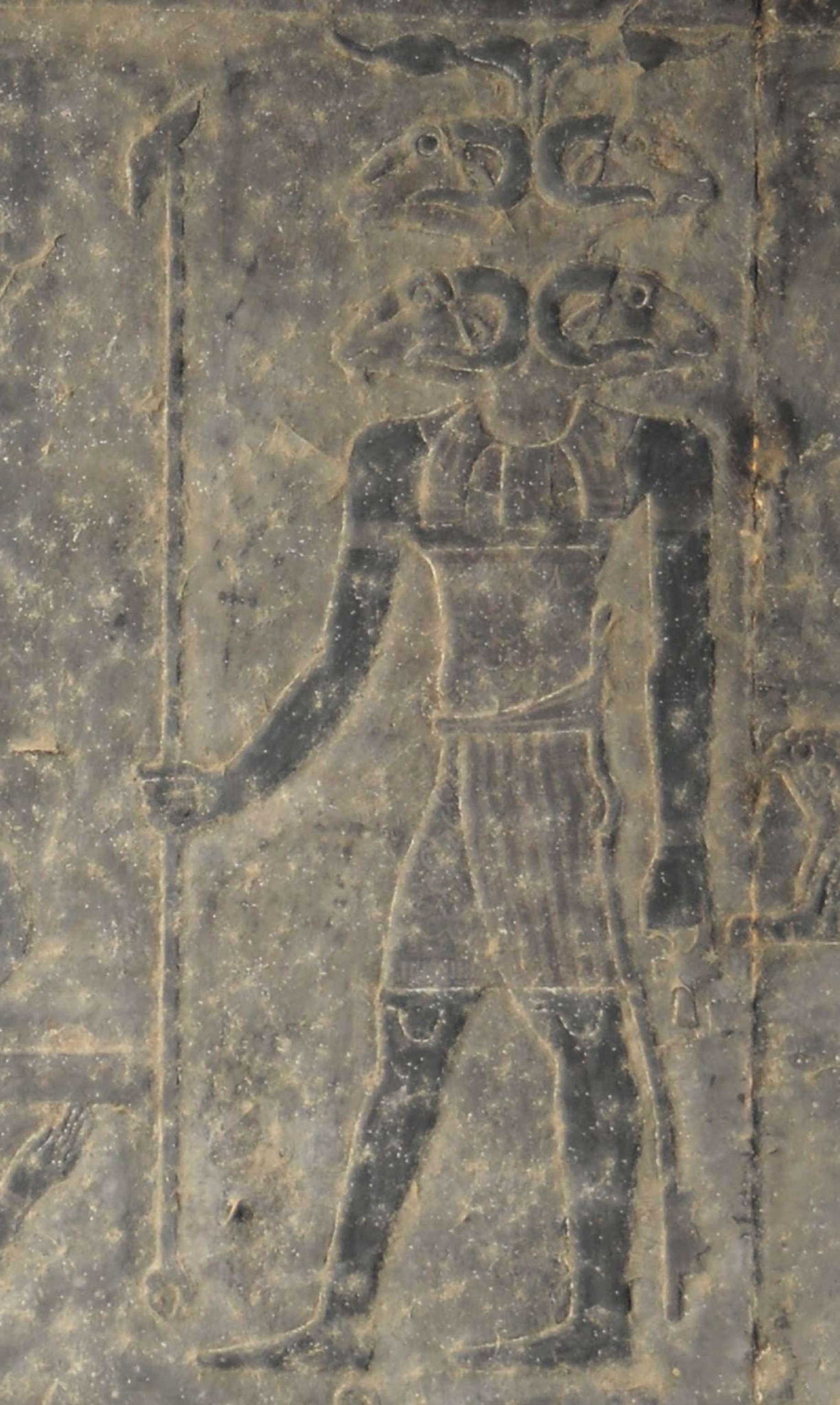 A soot-covered carving of a god with four rams heads