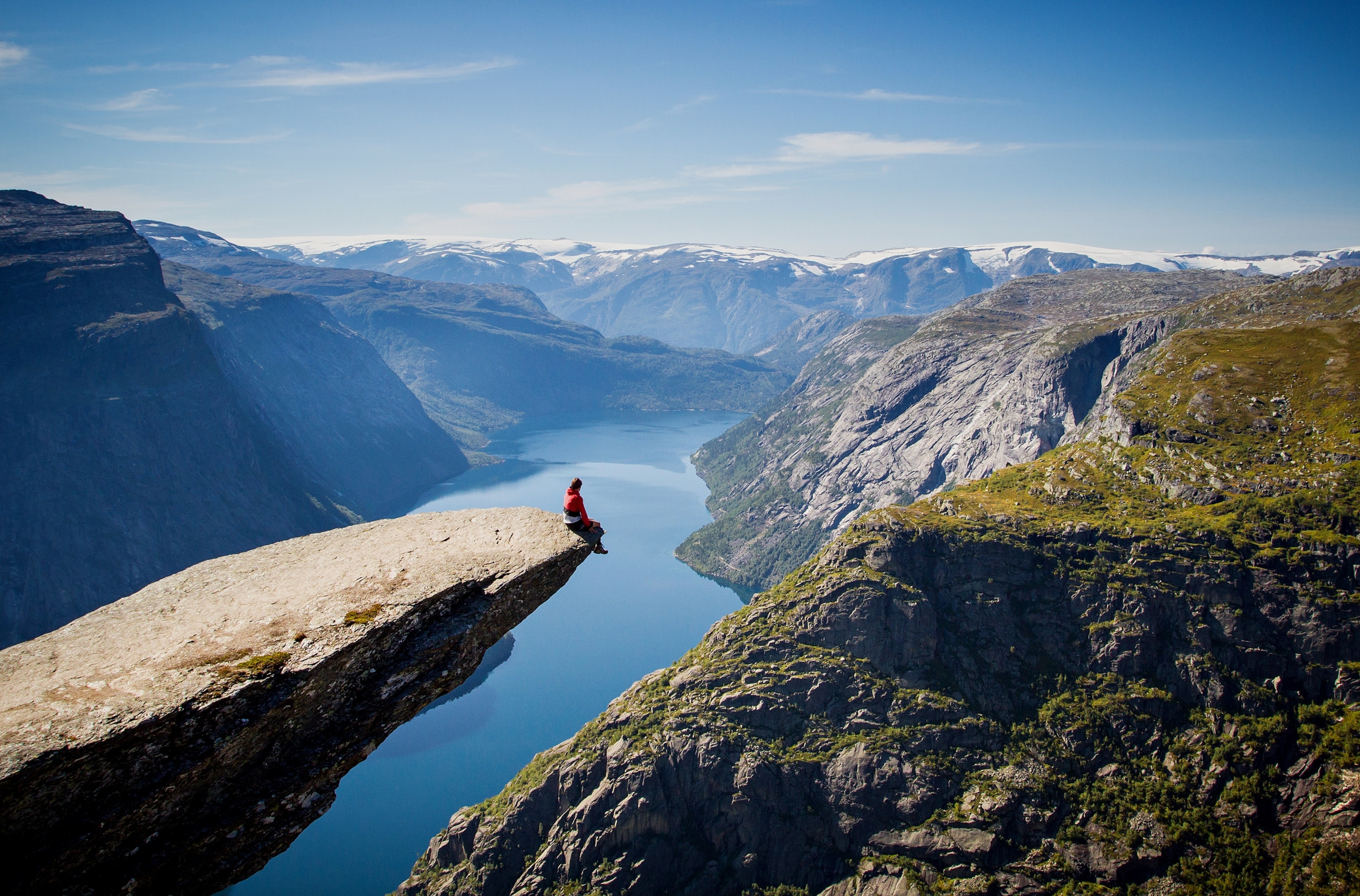 man sitting on Trolltunga rock above a Norwegian fjord