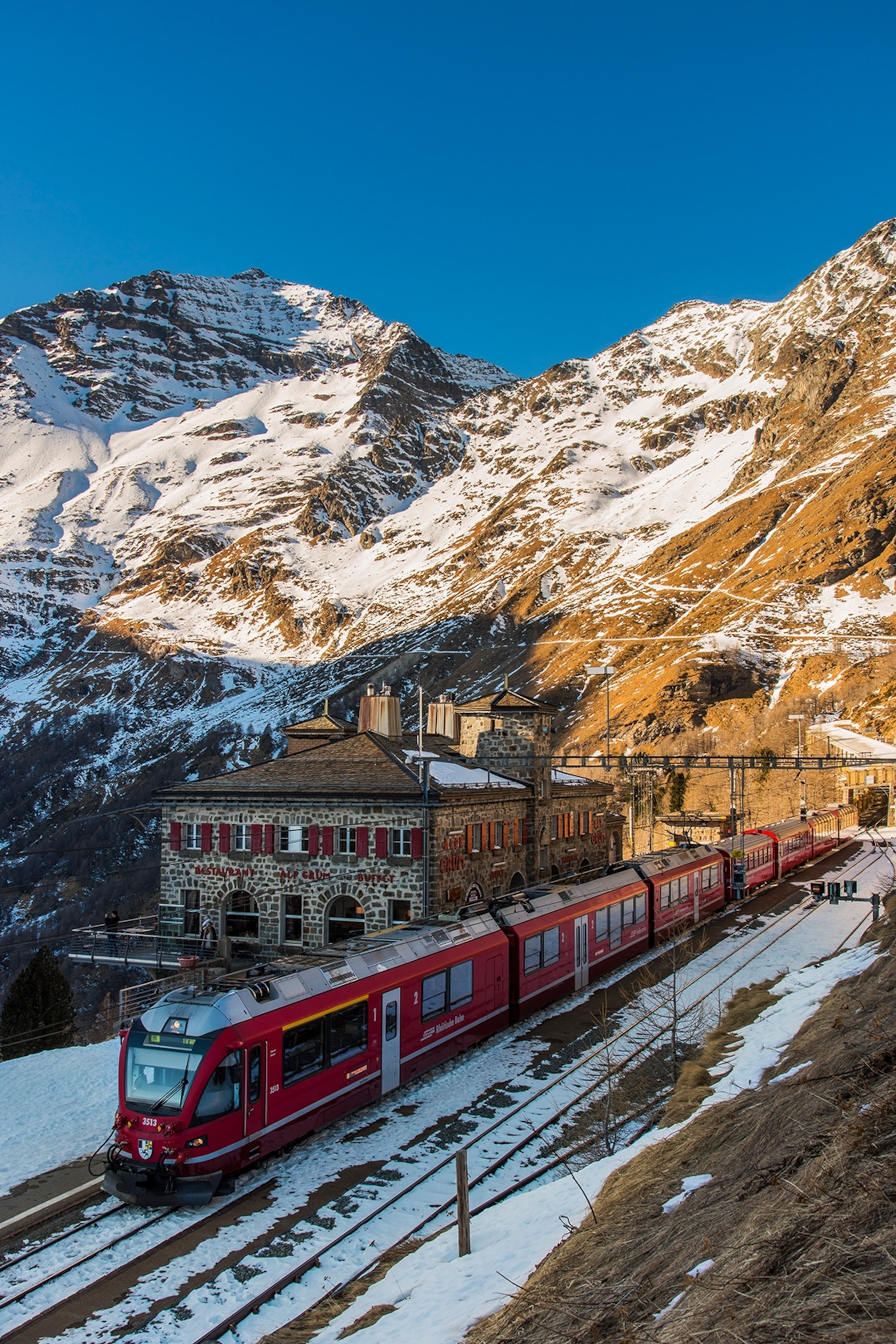 A modern train halting at a snowy mountain station.