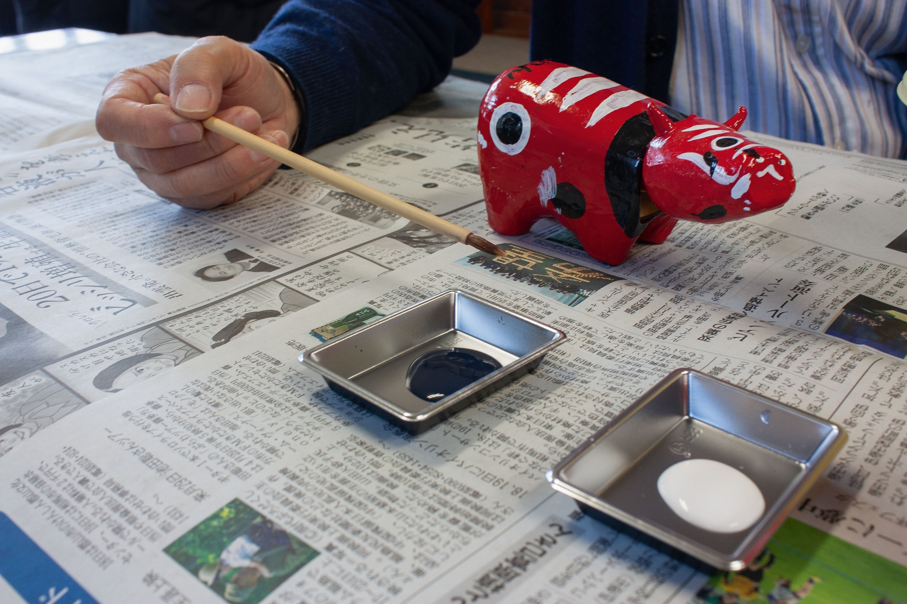 workers painting Fukushima's red cow with personal designs incorporated if red and black strokes and dots