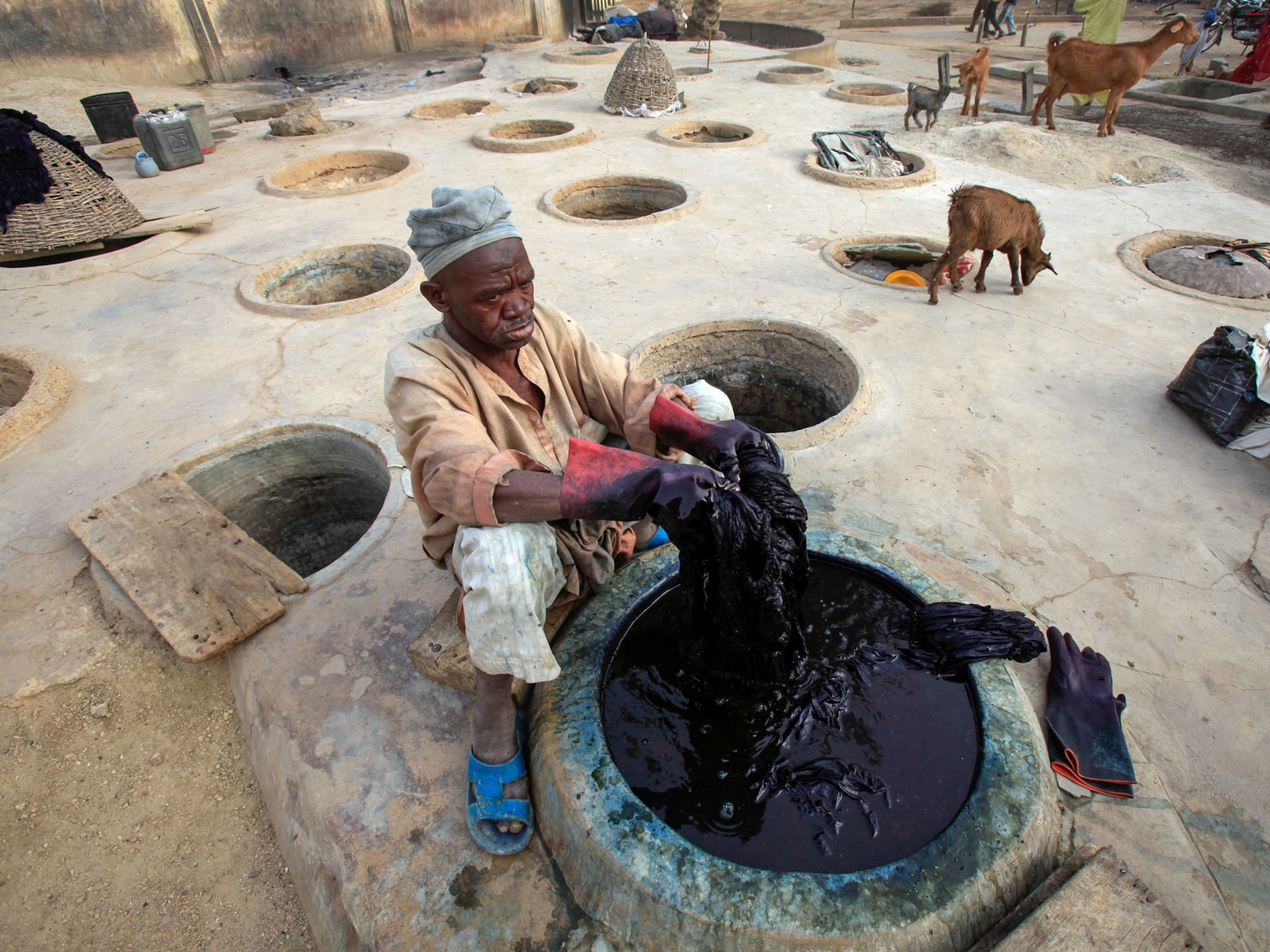 A man sits before one of dozens of concrete vats of indigo dye.