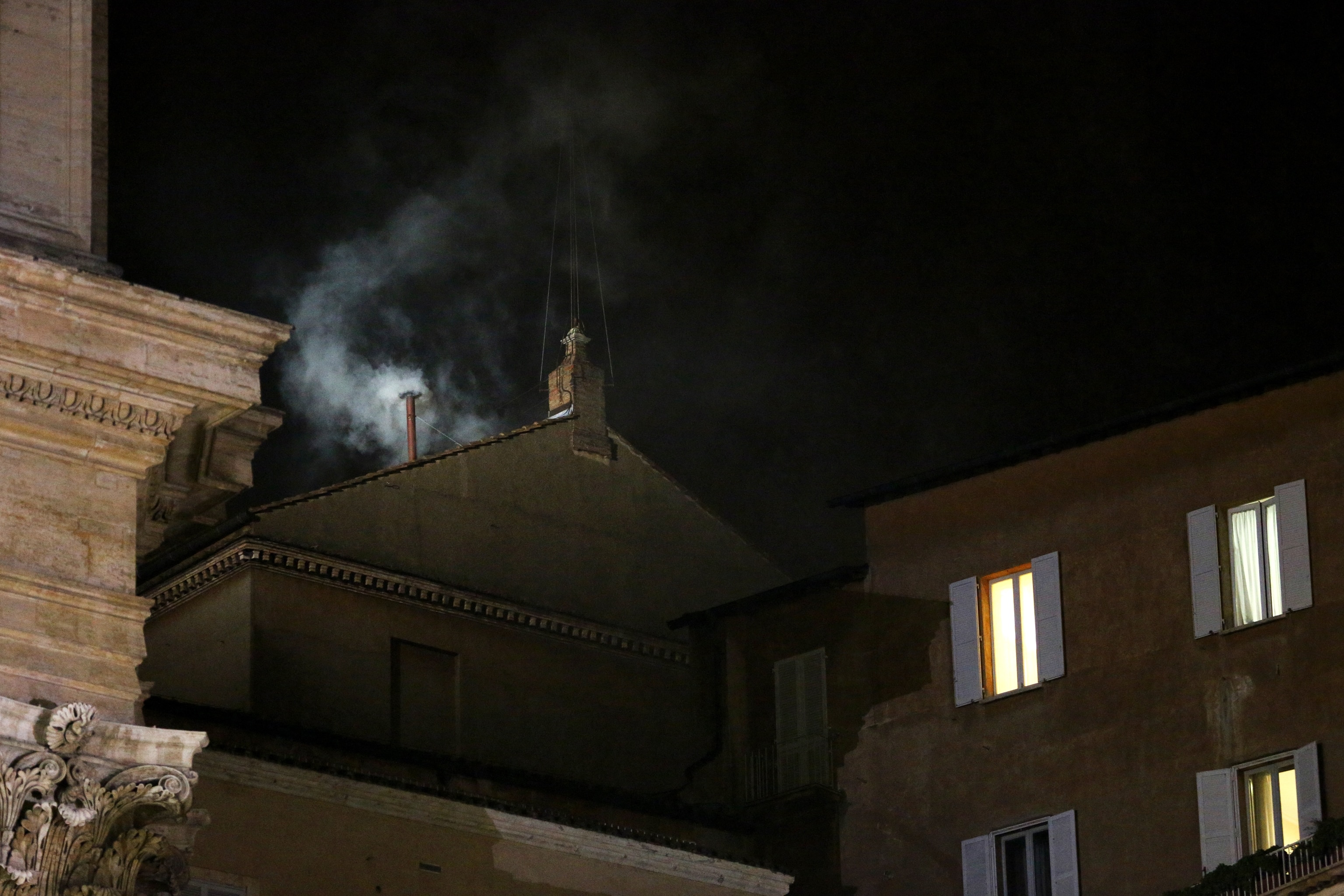 White smoke billows from the small chimney on the roof of the Sistine Chapel.
