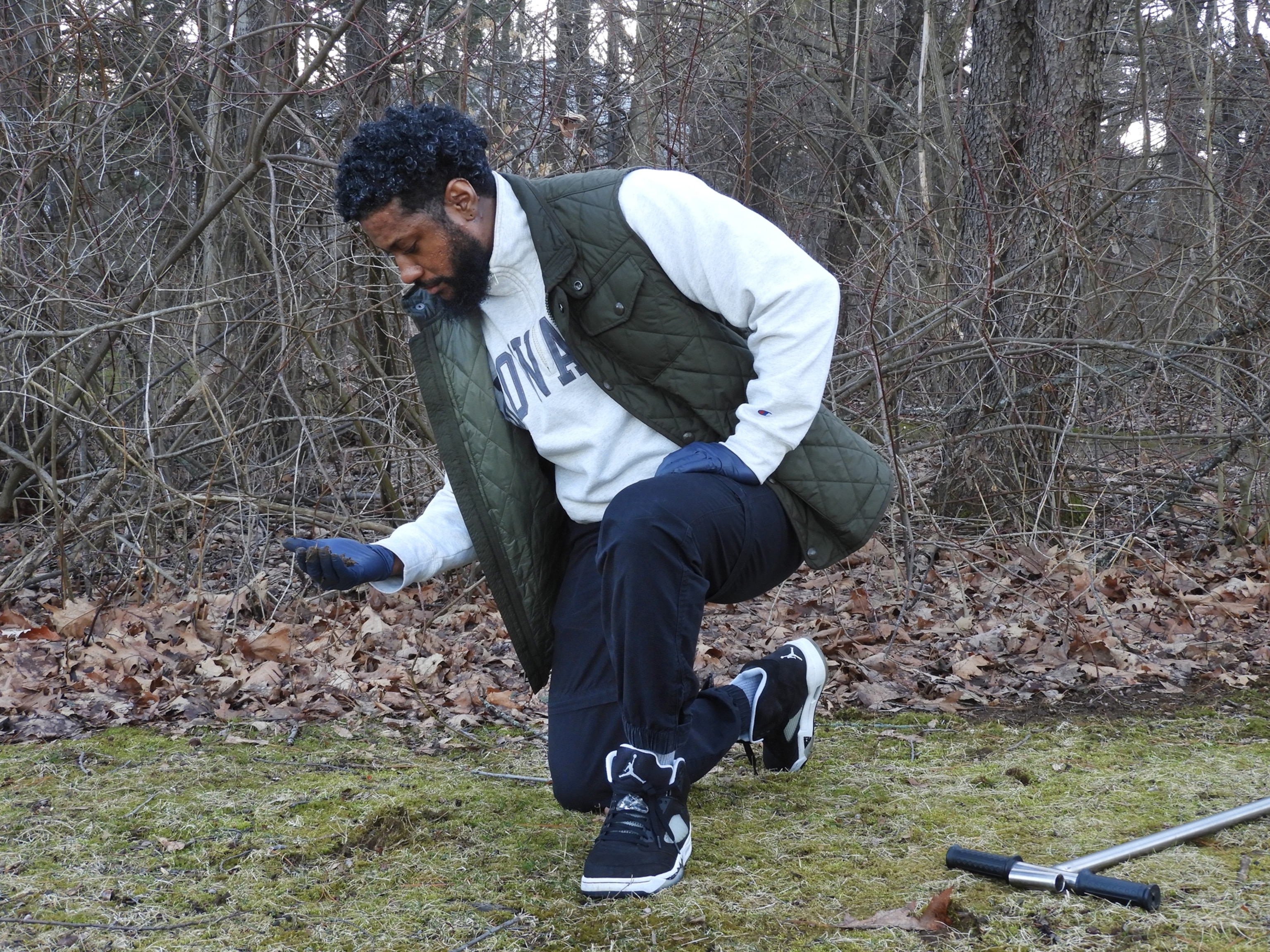 Picture of man crouching to pick up something from ground.