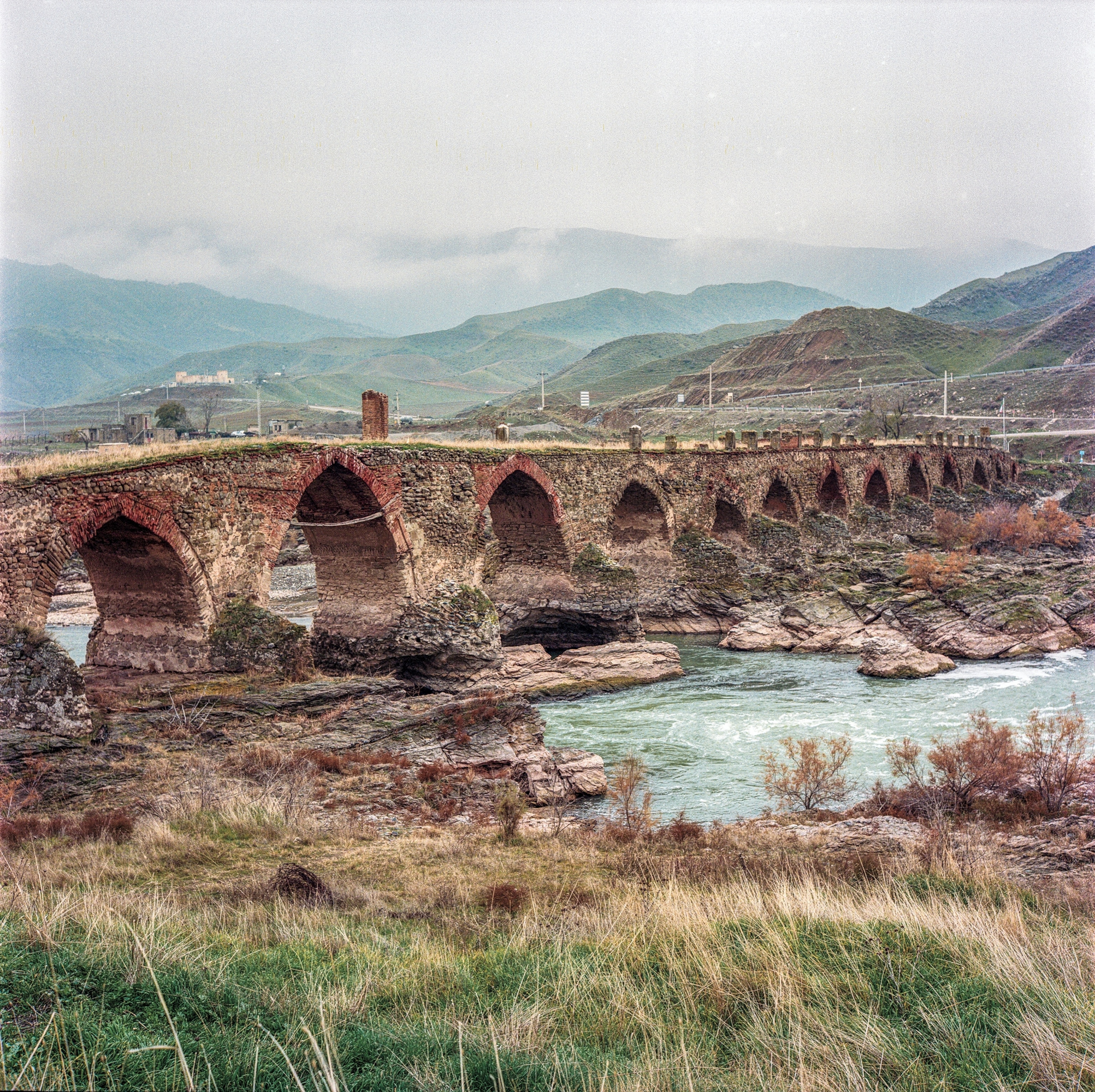 A bridge stands over water surrounded by mountains.