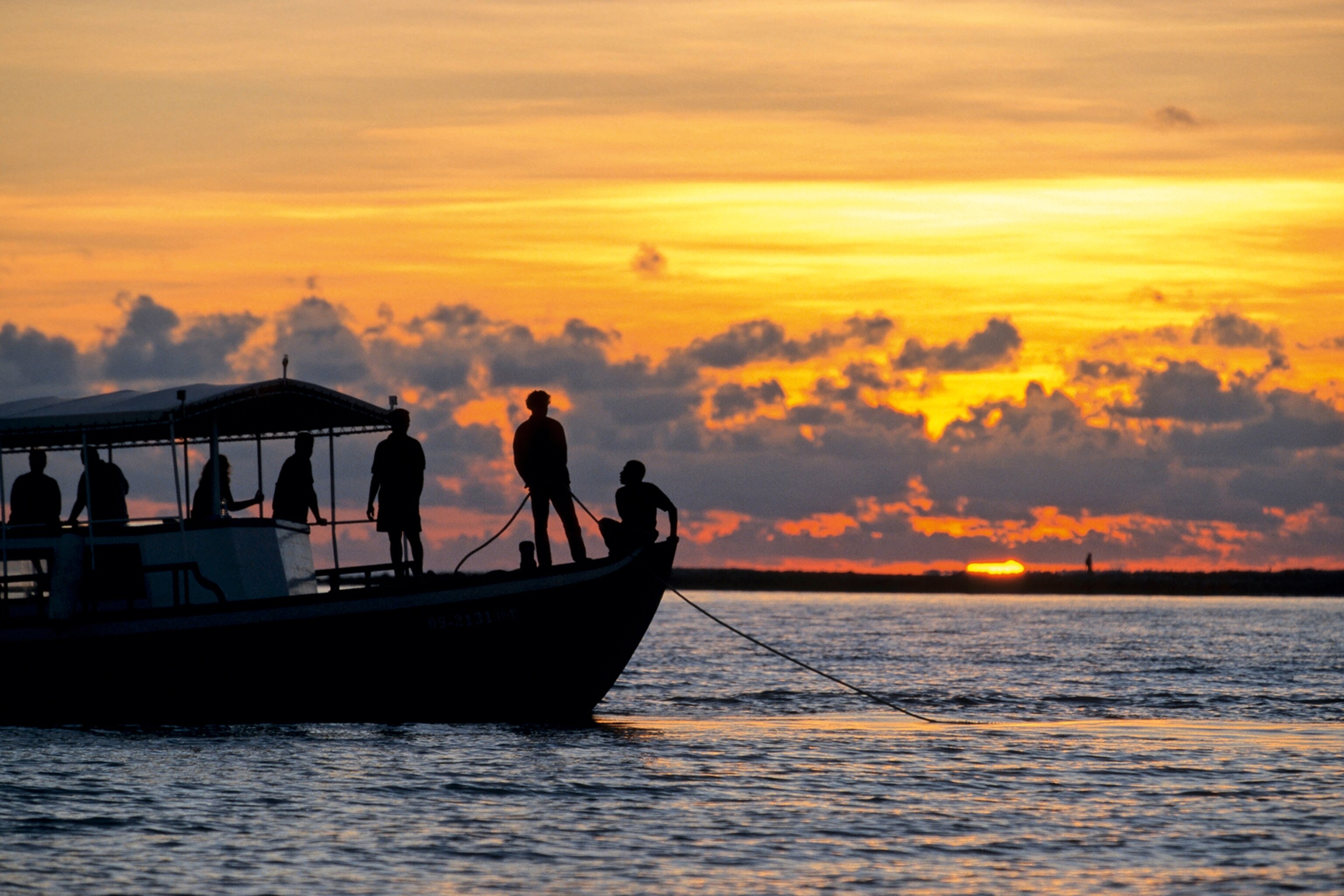 a boat full of people fishing at sunset