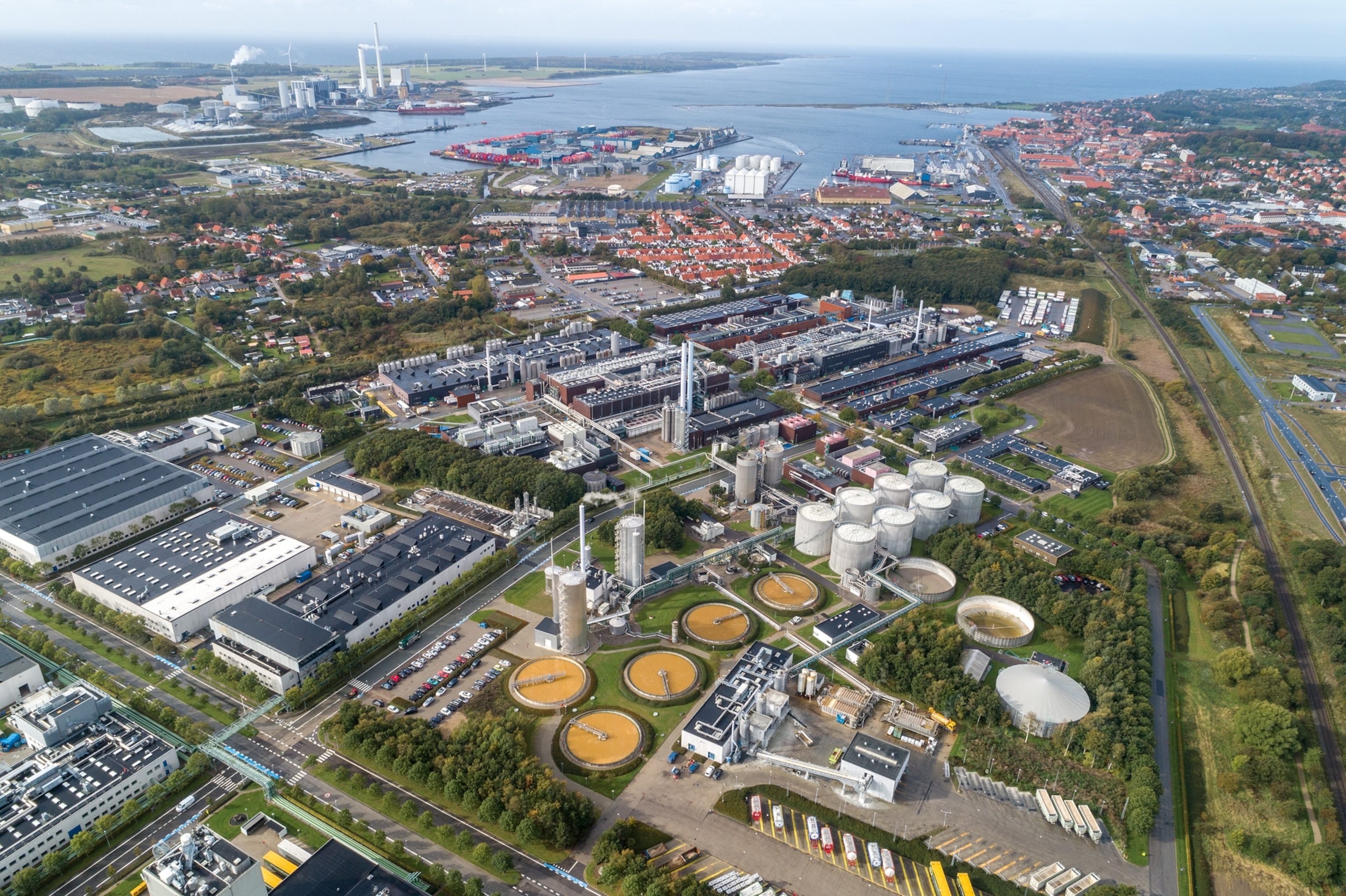 An aerial view of a factory site next to a large body of water