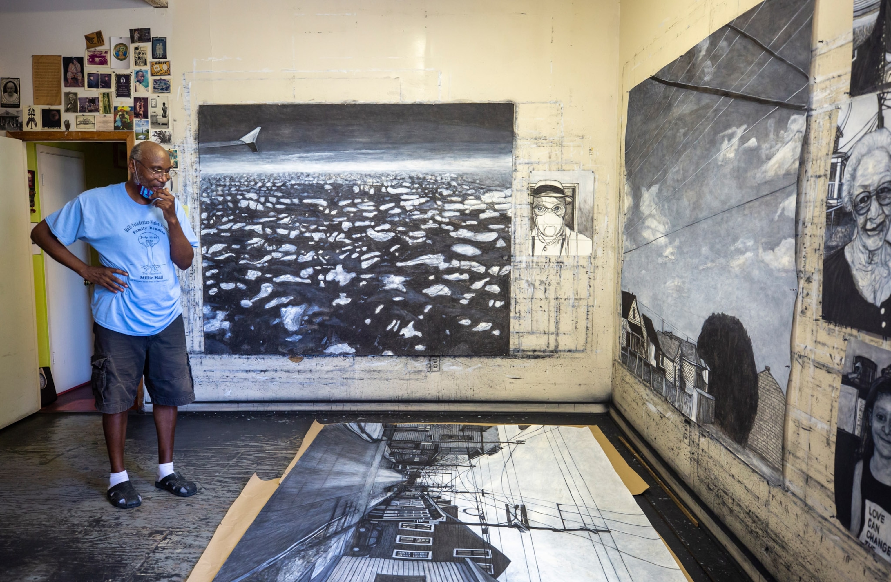 a man looking at a large canvas of artwork lying on the ground