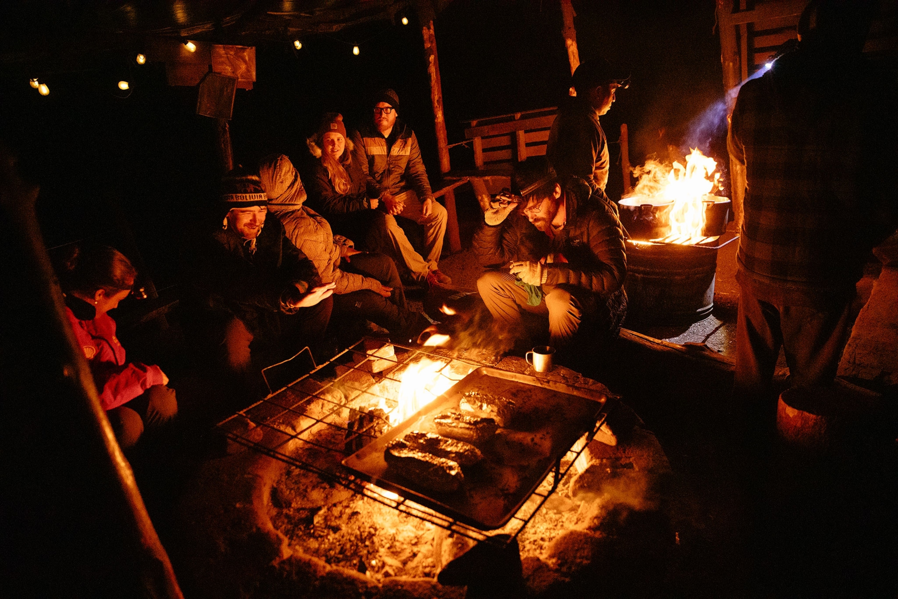 Hikers eat dinner in camp by fireside on the side of Acatenango.
