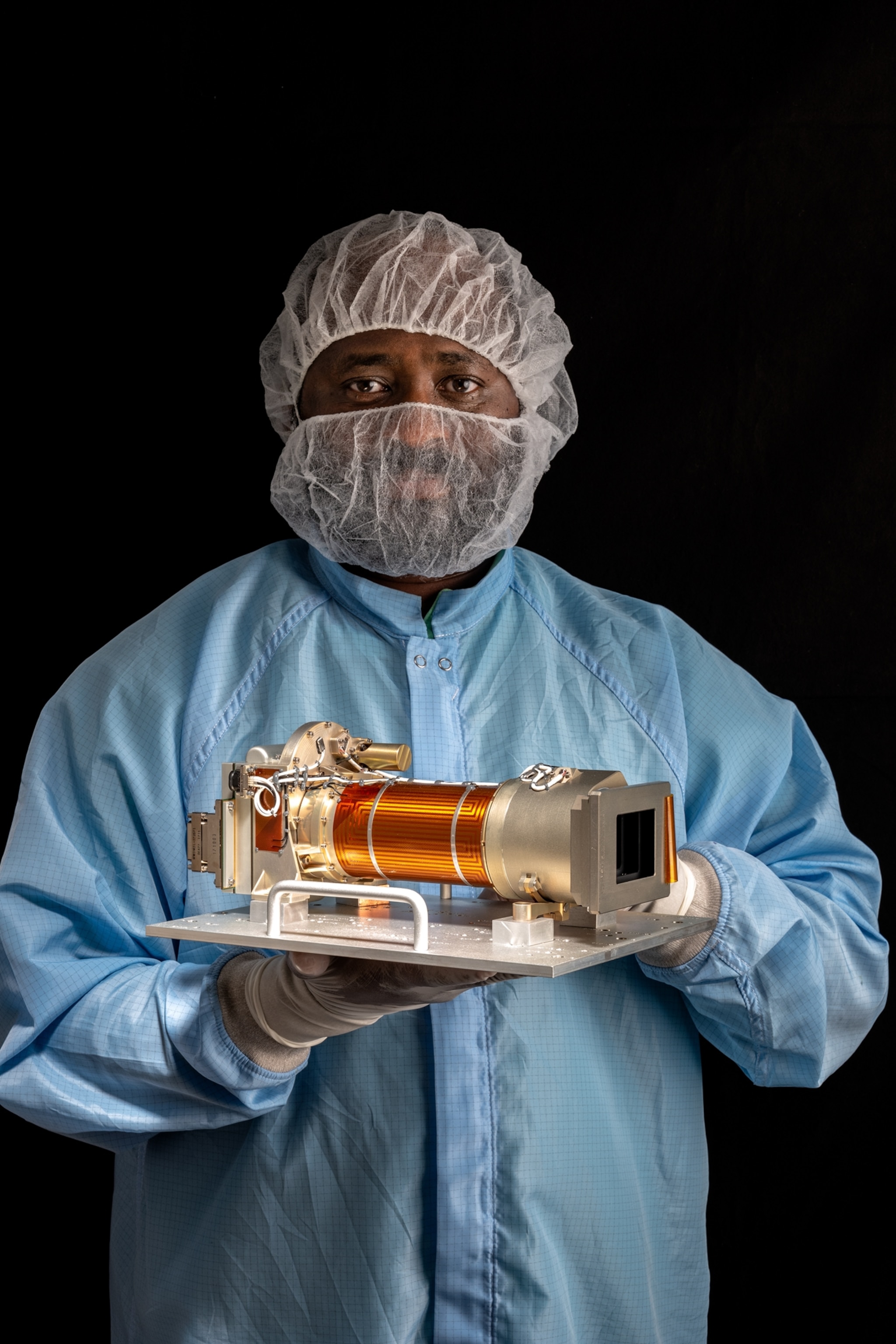 man in blue bodysuits and face cover holding an orange cylinder.