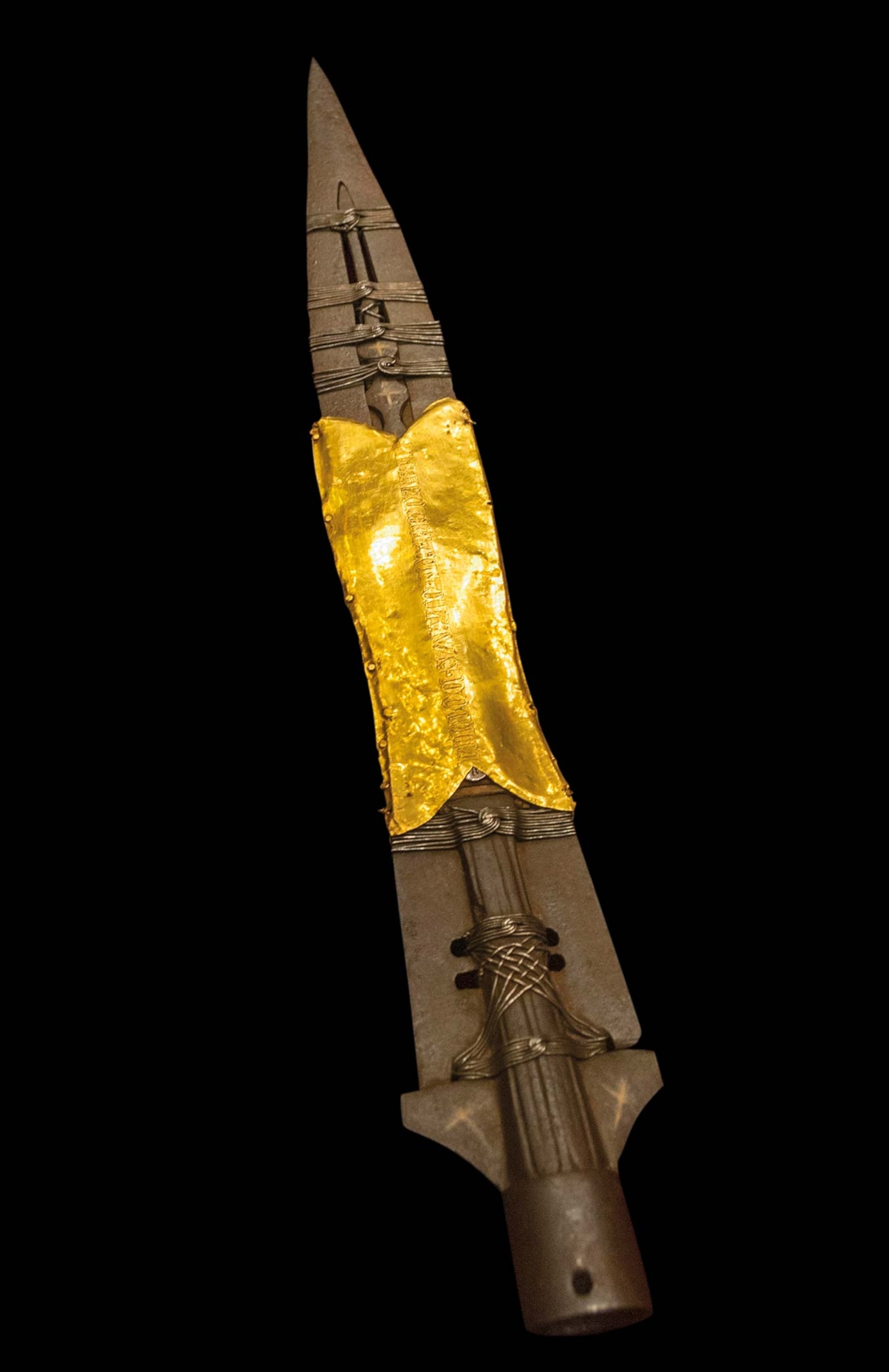 A metal lance, with a band of gold wrapped around the middle