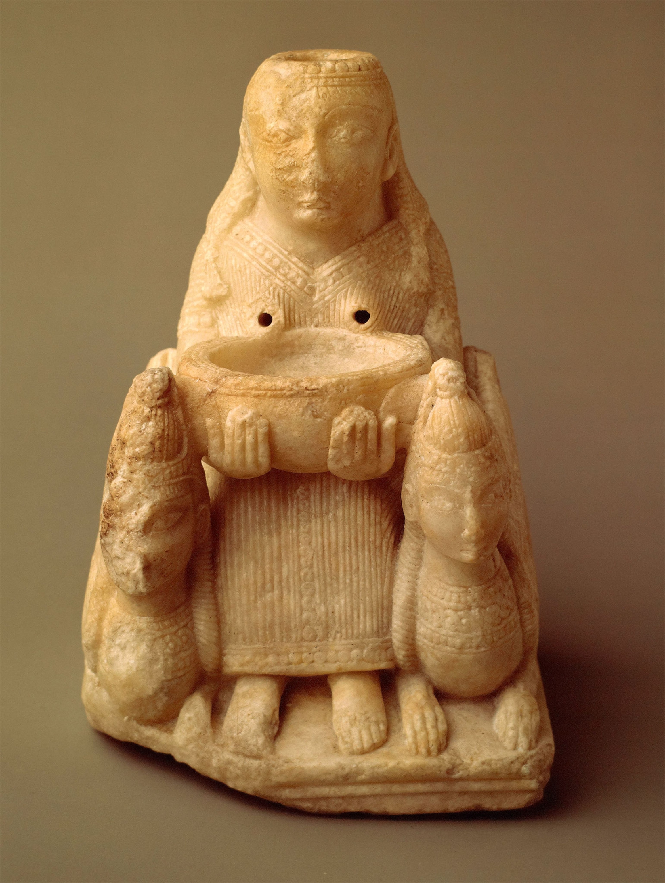 A statuette of a woman sitting while holding a bowl