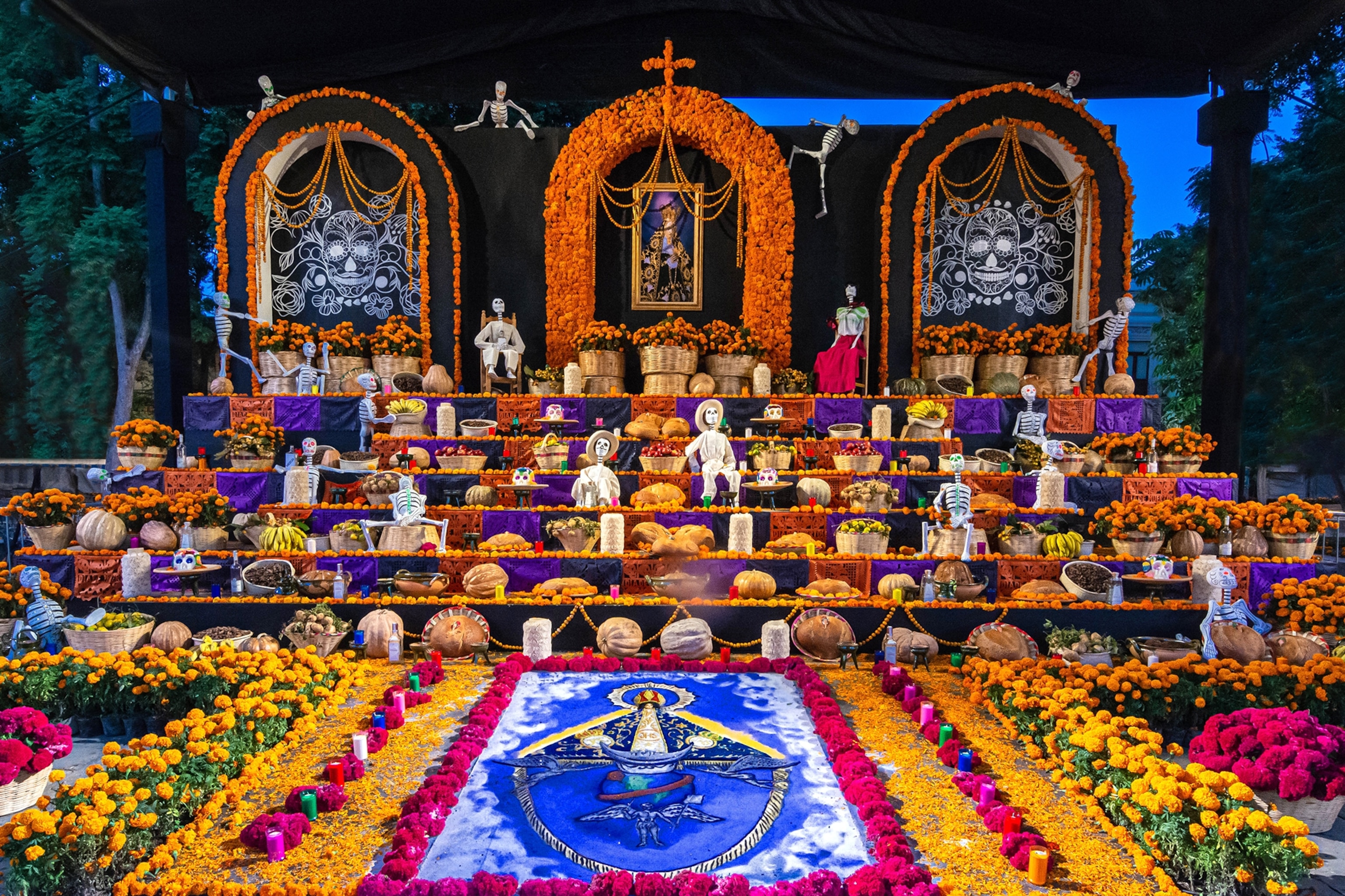 A colourful and impressively wide altar decked in flowers, skeletons and religious symbols.