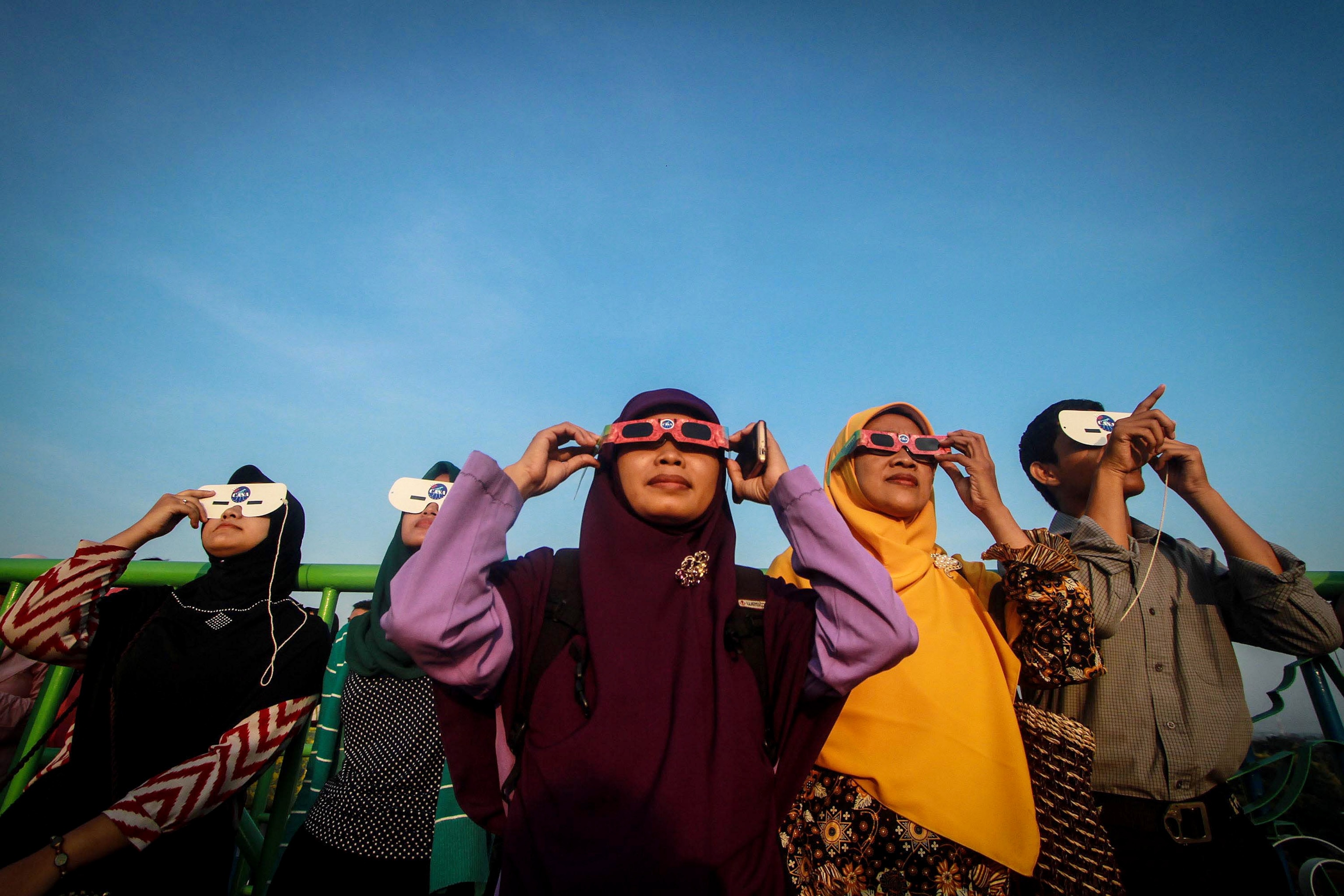 people using protective glasses to view a solar eclipse in Surakarta, Indonesia