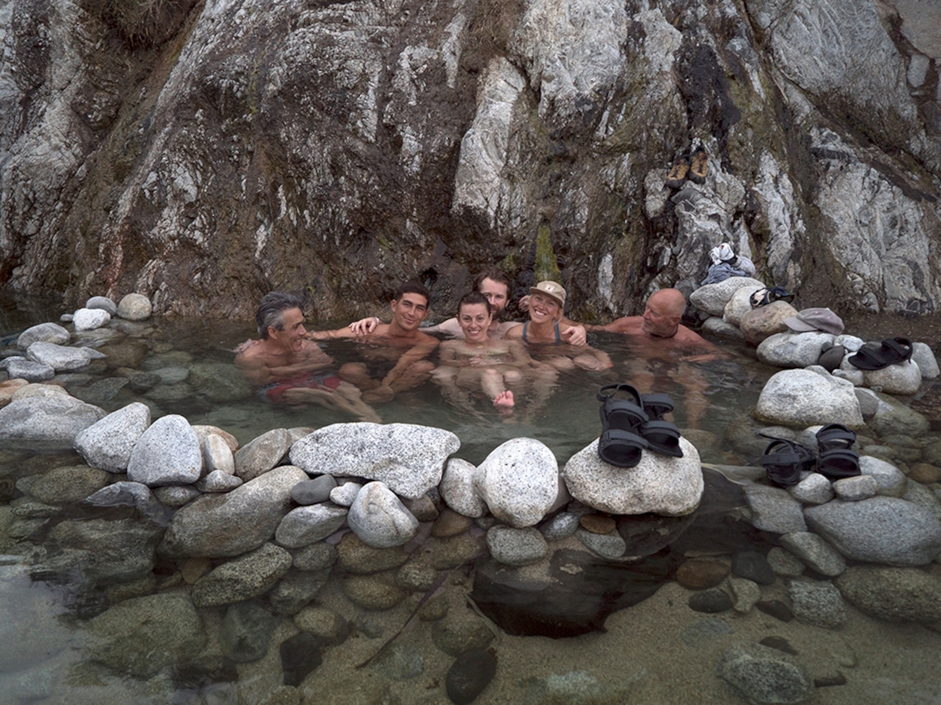 a group of friends soaking in the natural springs in Aguas Calientes, Baja, Mexico