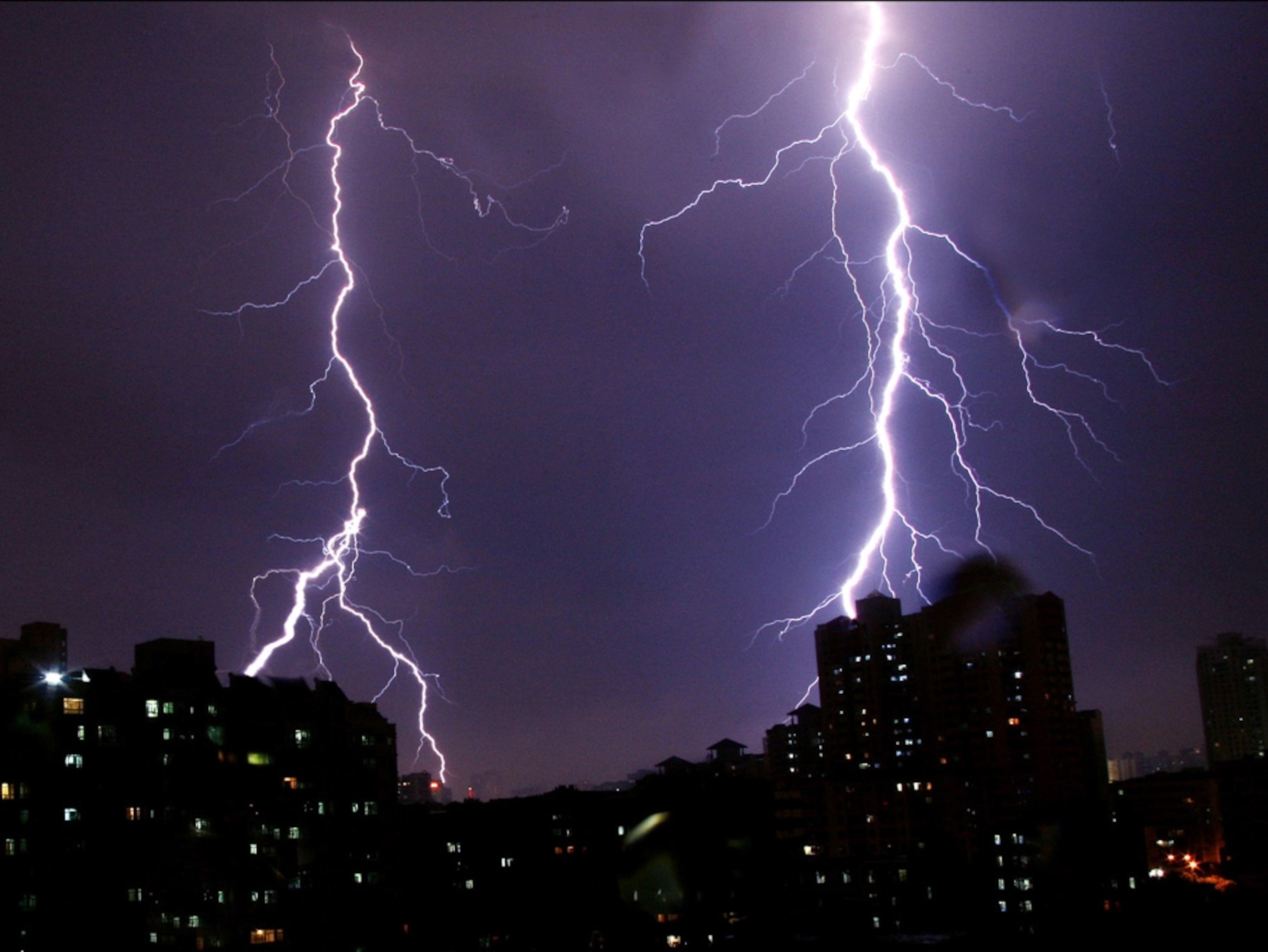 Lightning strikes in two places behind a city skyline