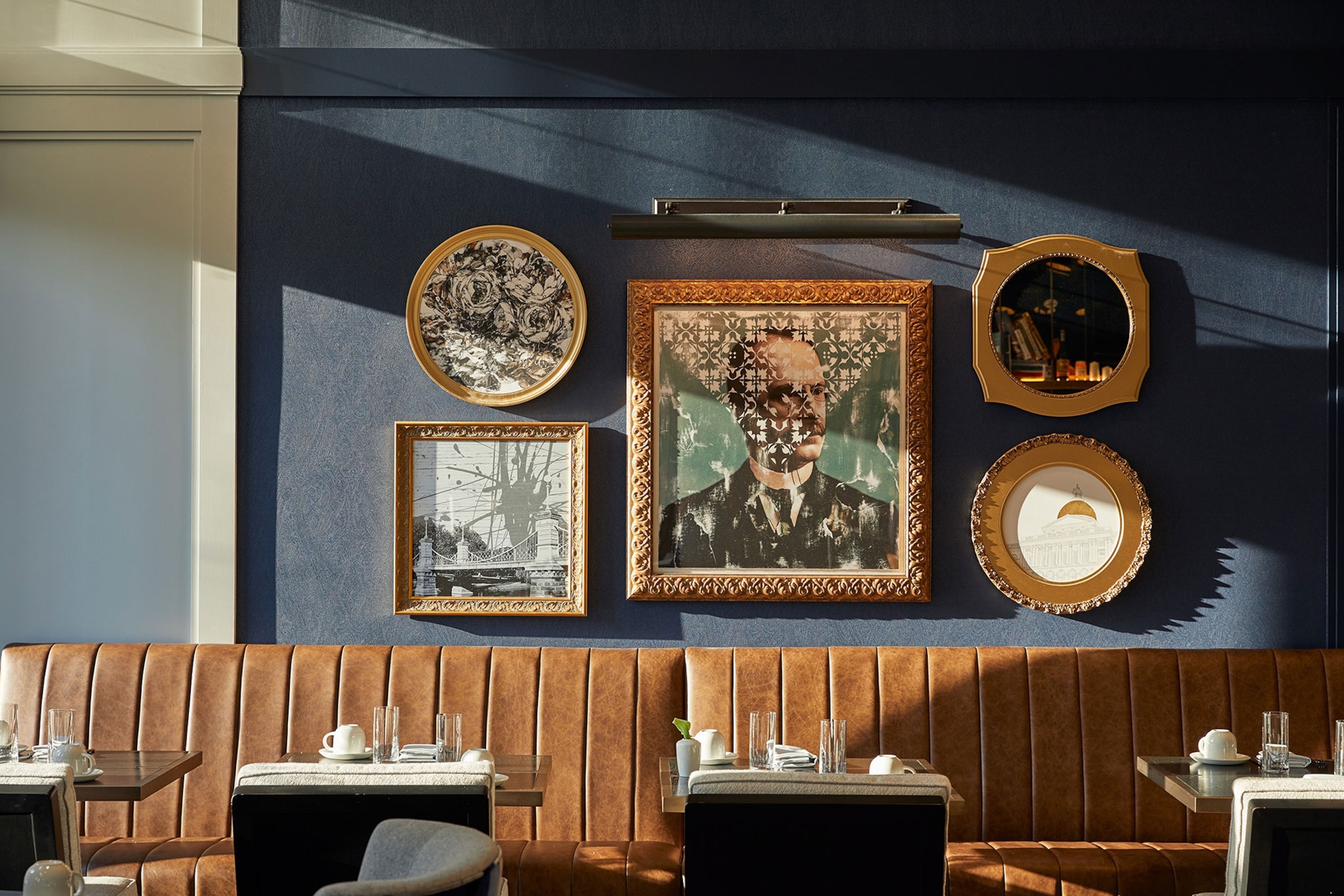 interior of restaurant with set tables, artwork on the wall and leather furniture