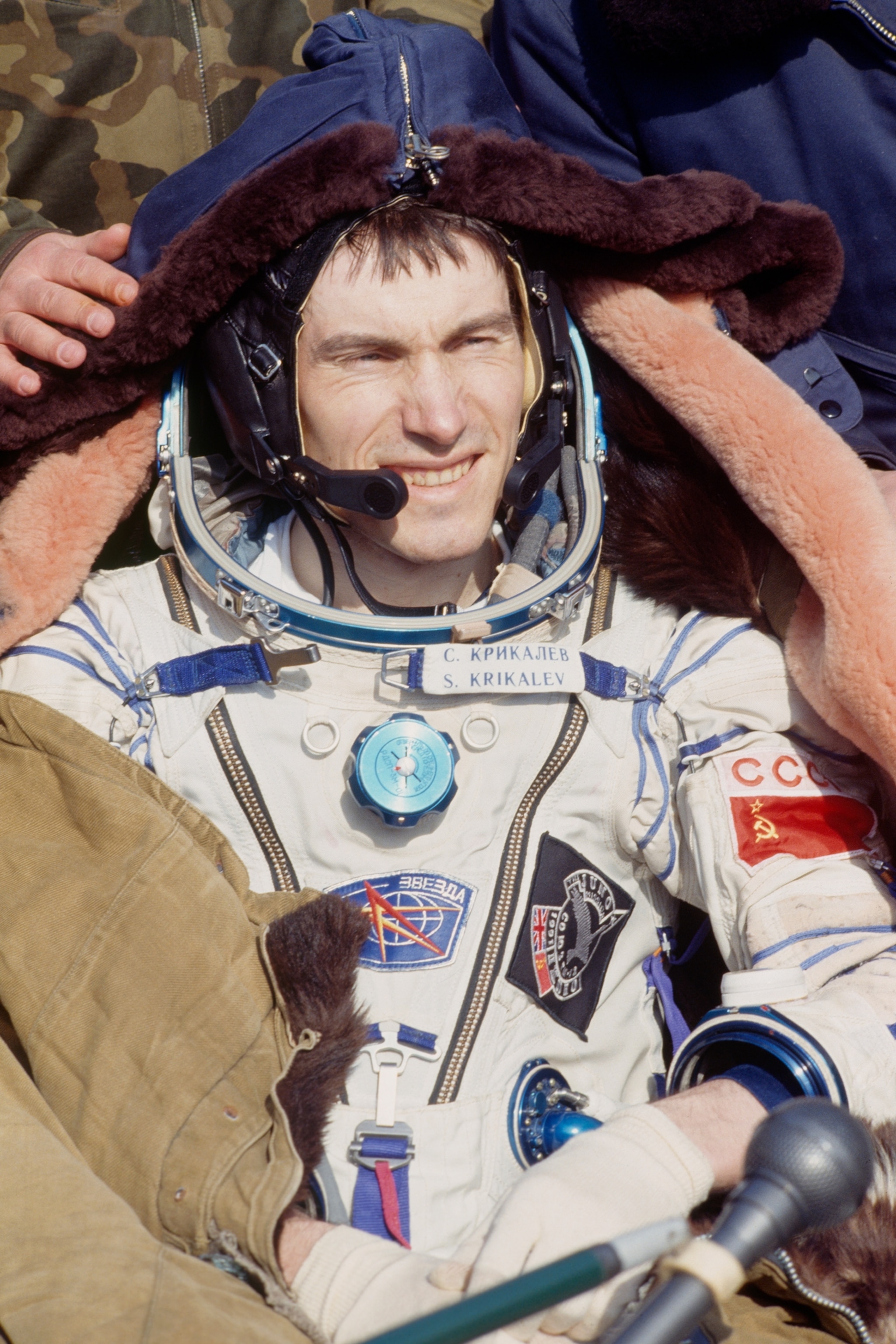Man in white space suit smiling at the sun.