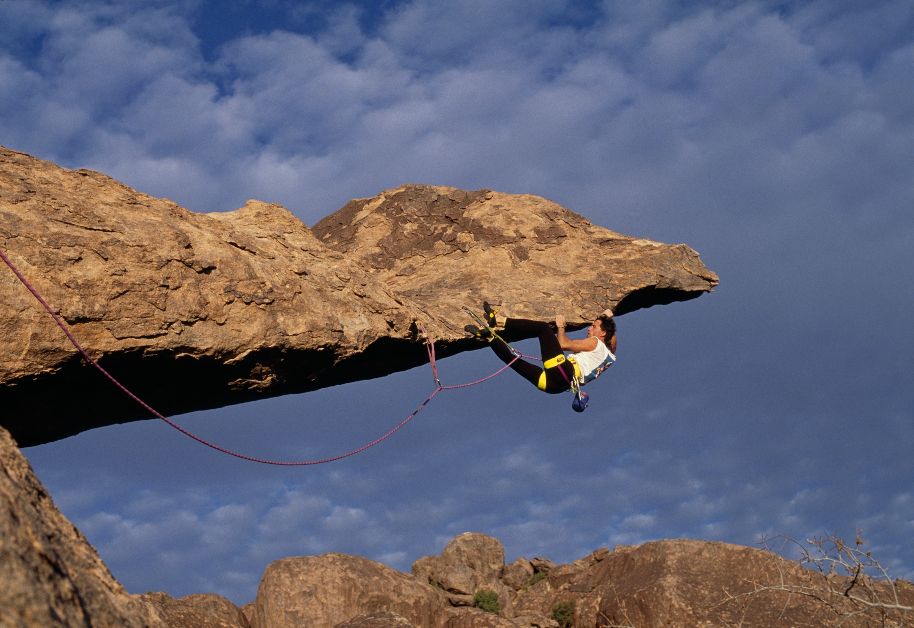 A climber clings to a long jagged outcrop.