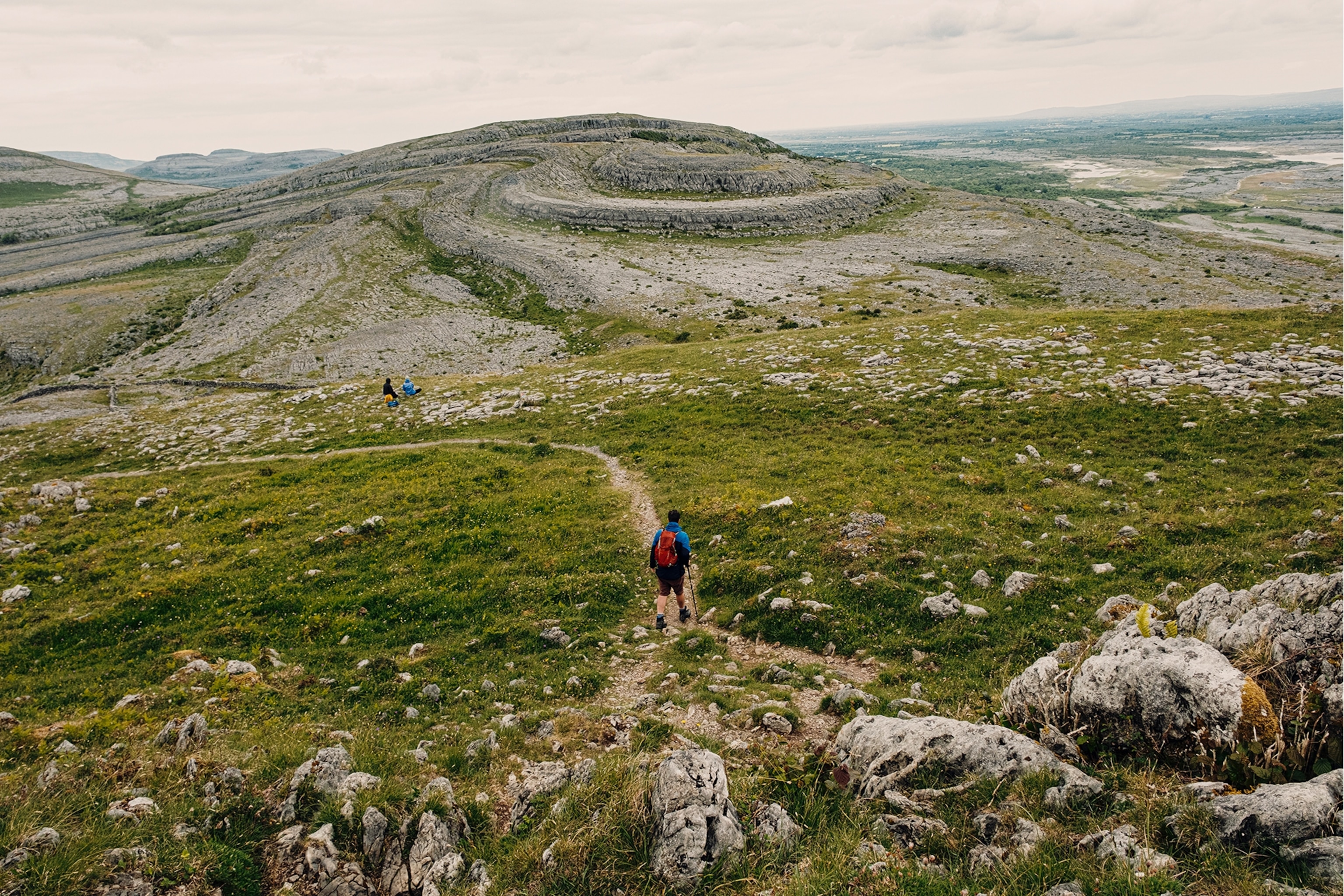 People hiking upon rocky grassland hills