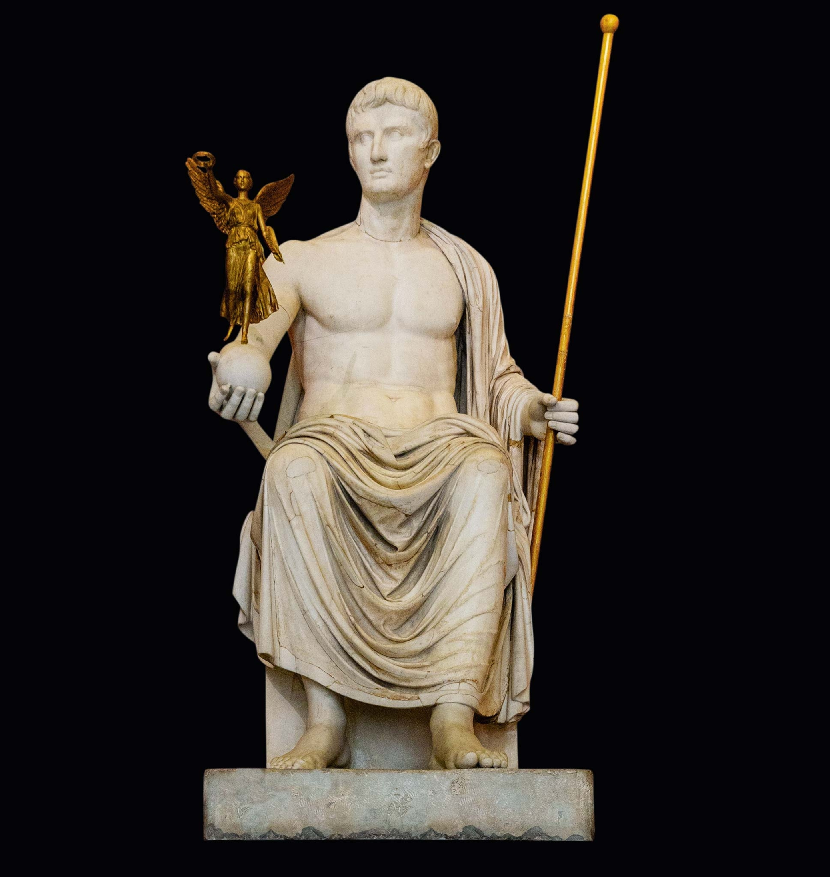 Emperor Augustus is portrayed as Jupiter, the Roman god of thunder and sky. He holds the winged victory (or Nike) in his right hand and the scepter in his left—neither of which are original.