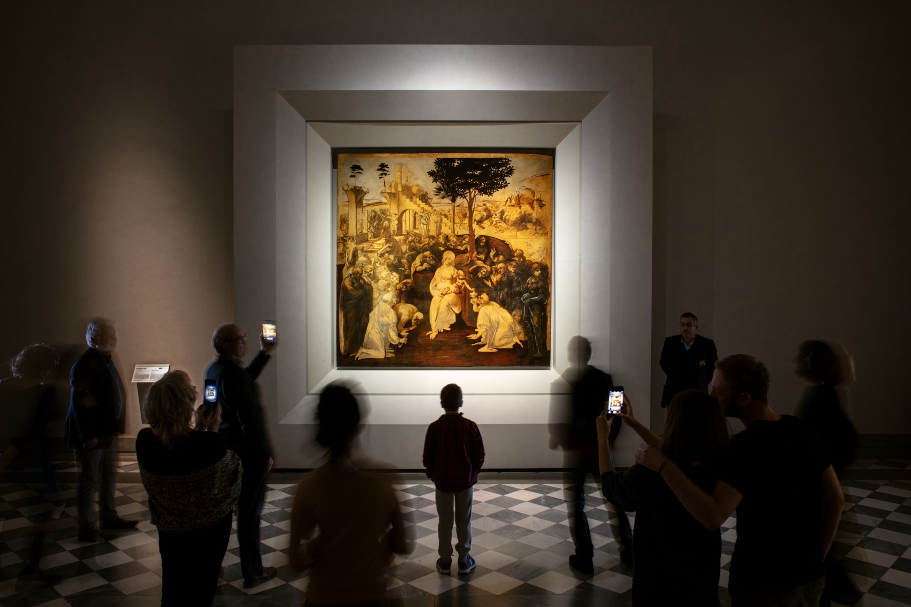 a long exposure of people looking and taking photos of a painting with a boy in focus