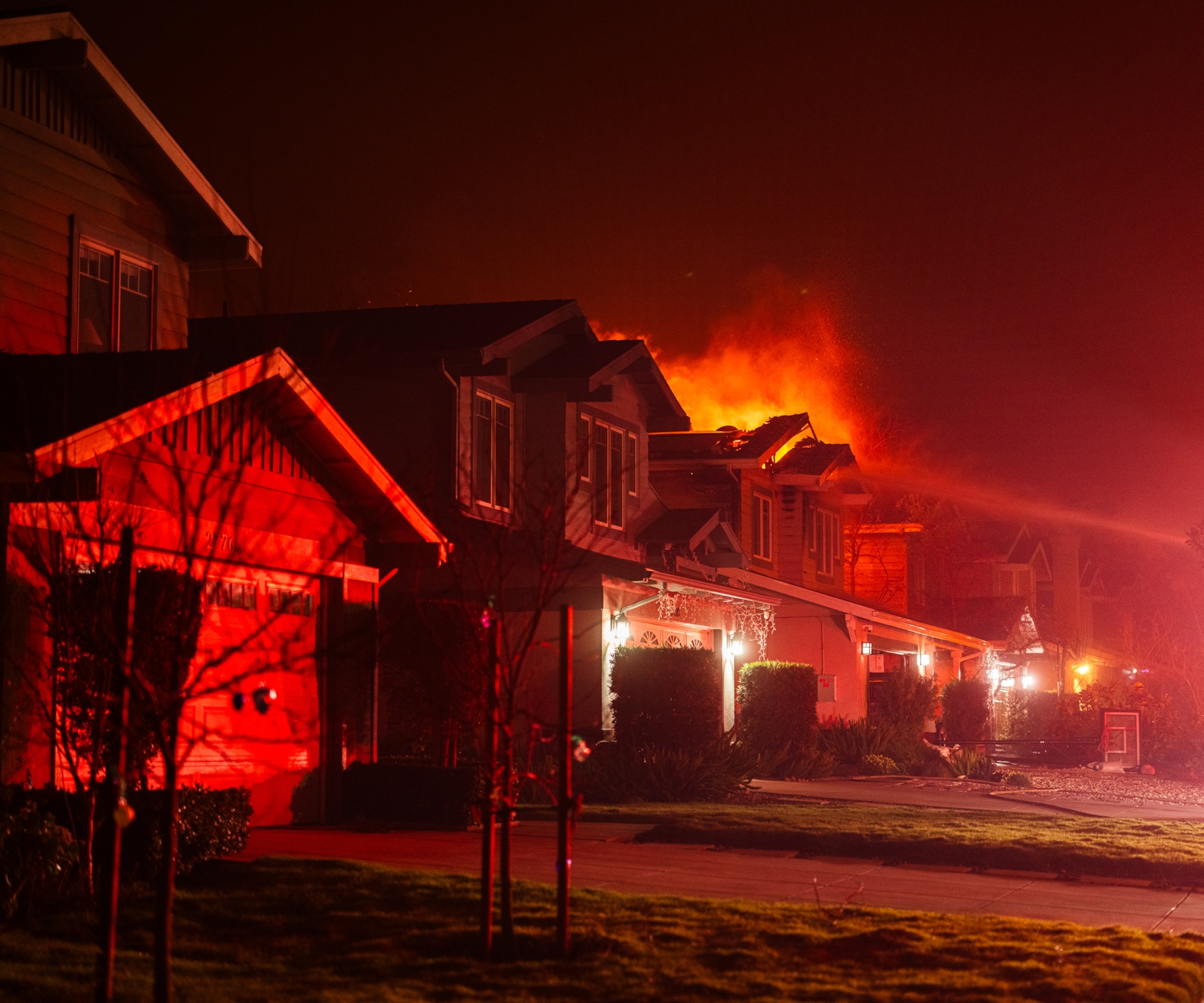A stream of water hitting a burning house.