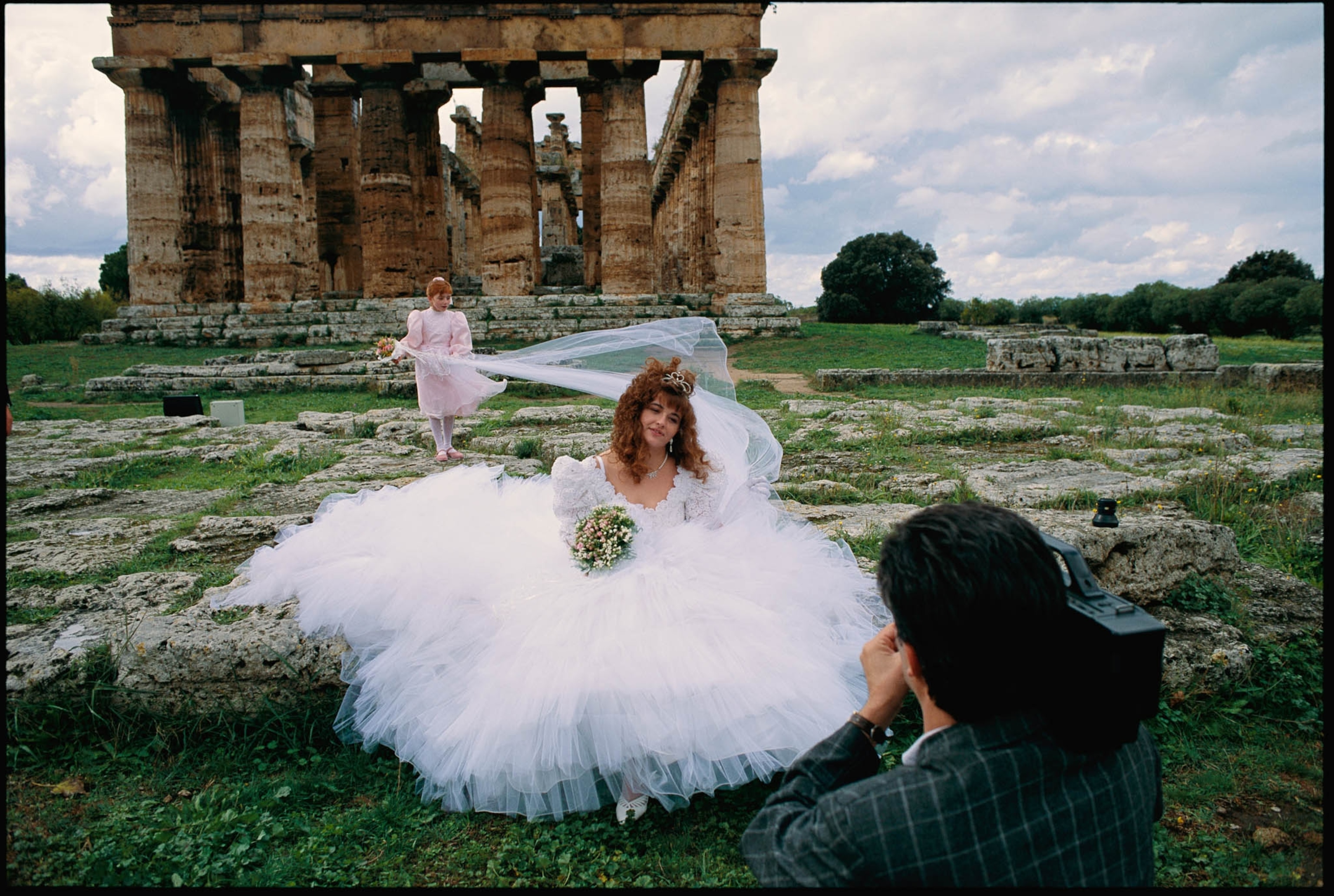 a woman in a wedding dress sitting in front of an ancient temple