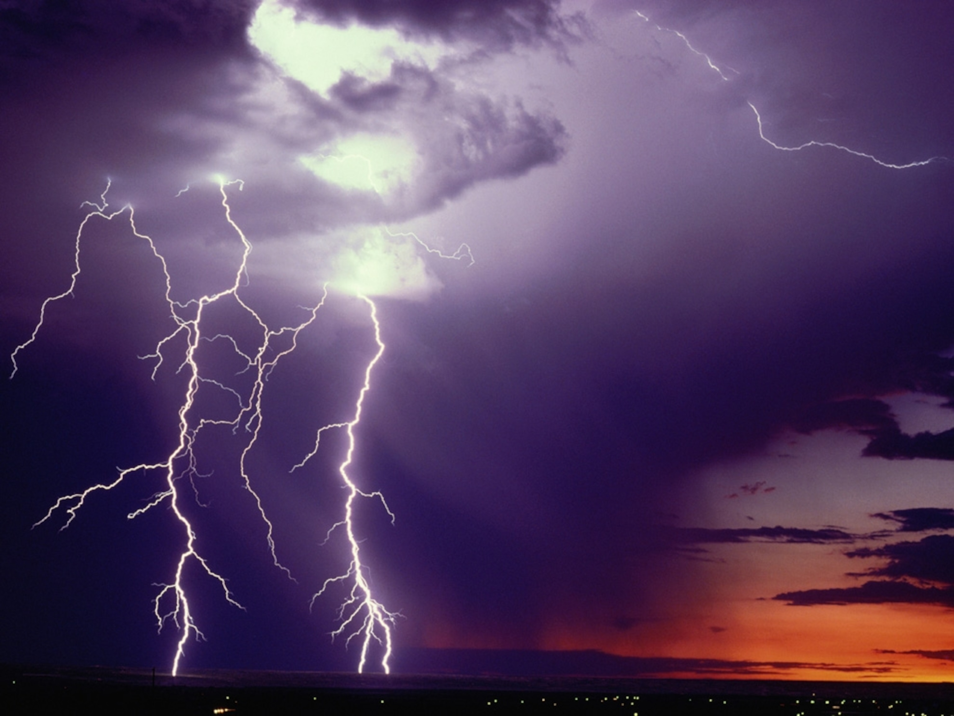 Two lightning bolts hit the ground in front of storm clouds