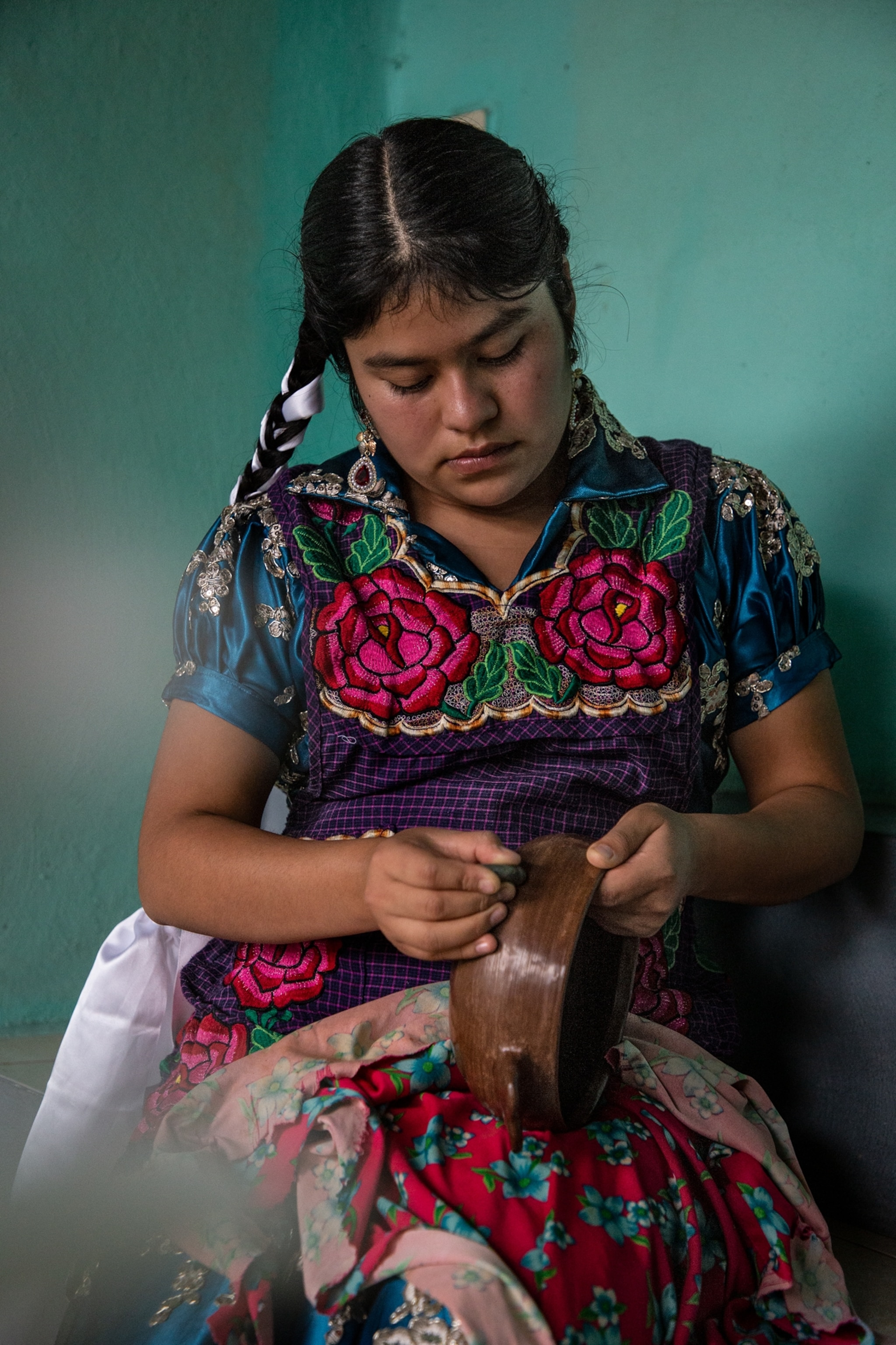 a woman burnishes a piece of red pottery by hand