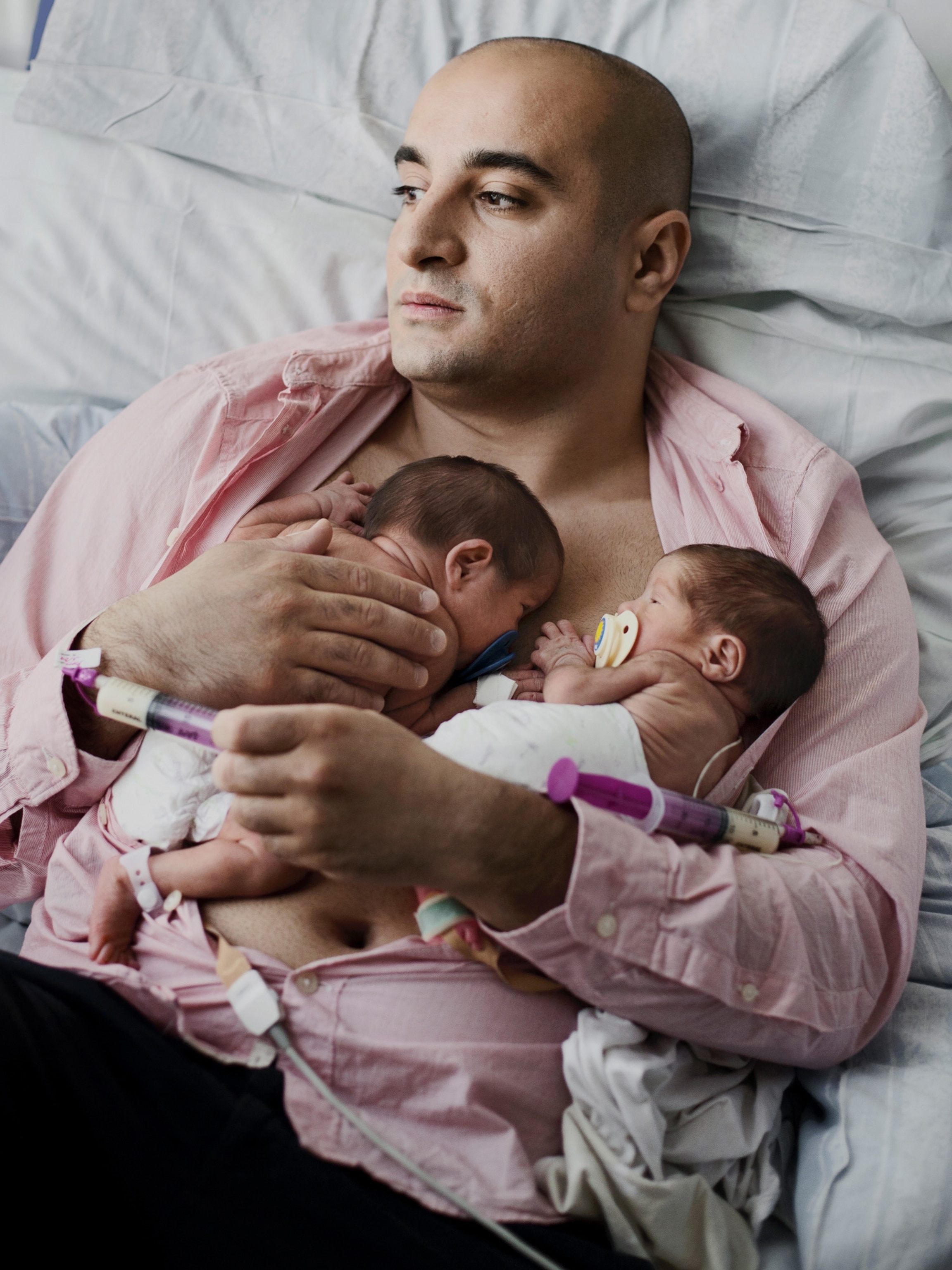 a father holding his two newborn babies on his chest
