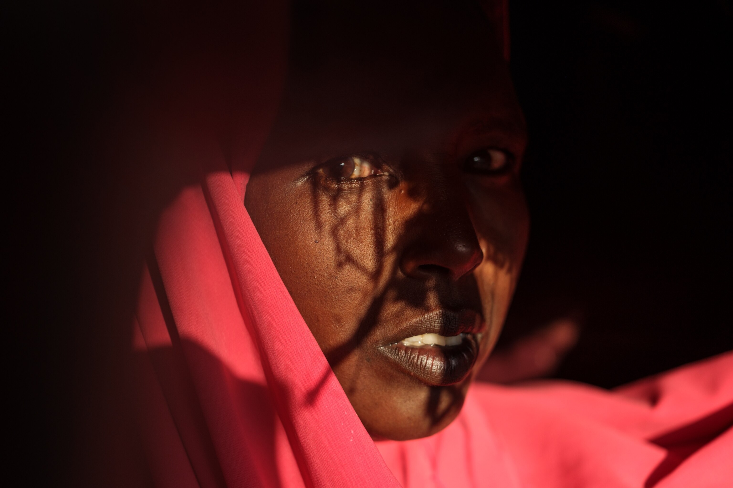 a woman with a bright pink headscarf looking into the camera